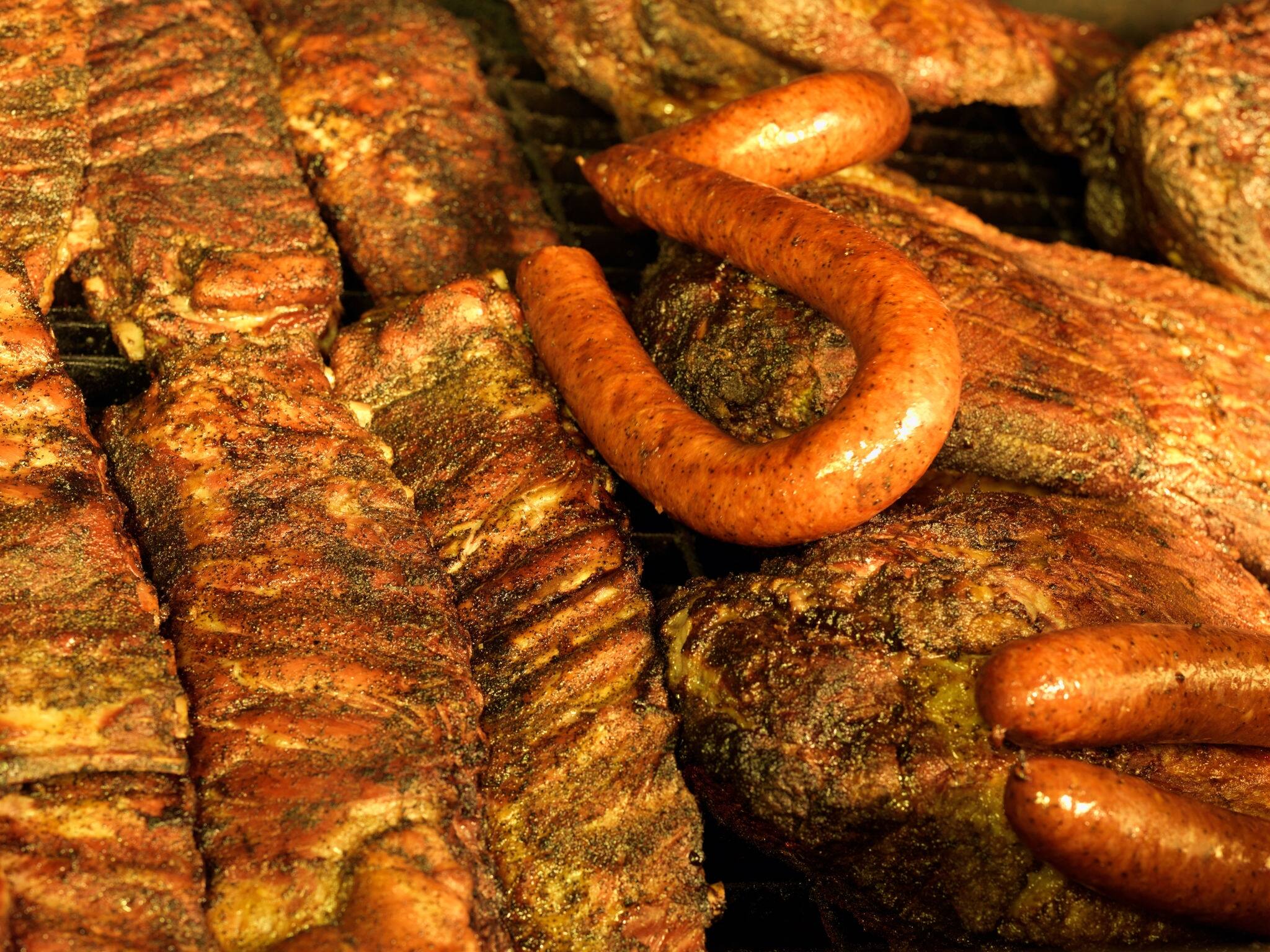Ribs, and beef brisket grilling in an open pit BBQ grill in Texas BBQ style, Houston, Texas, United States of America, North America