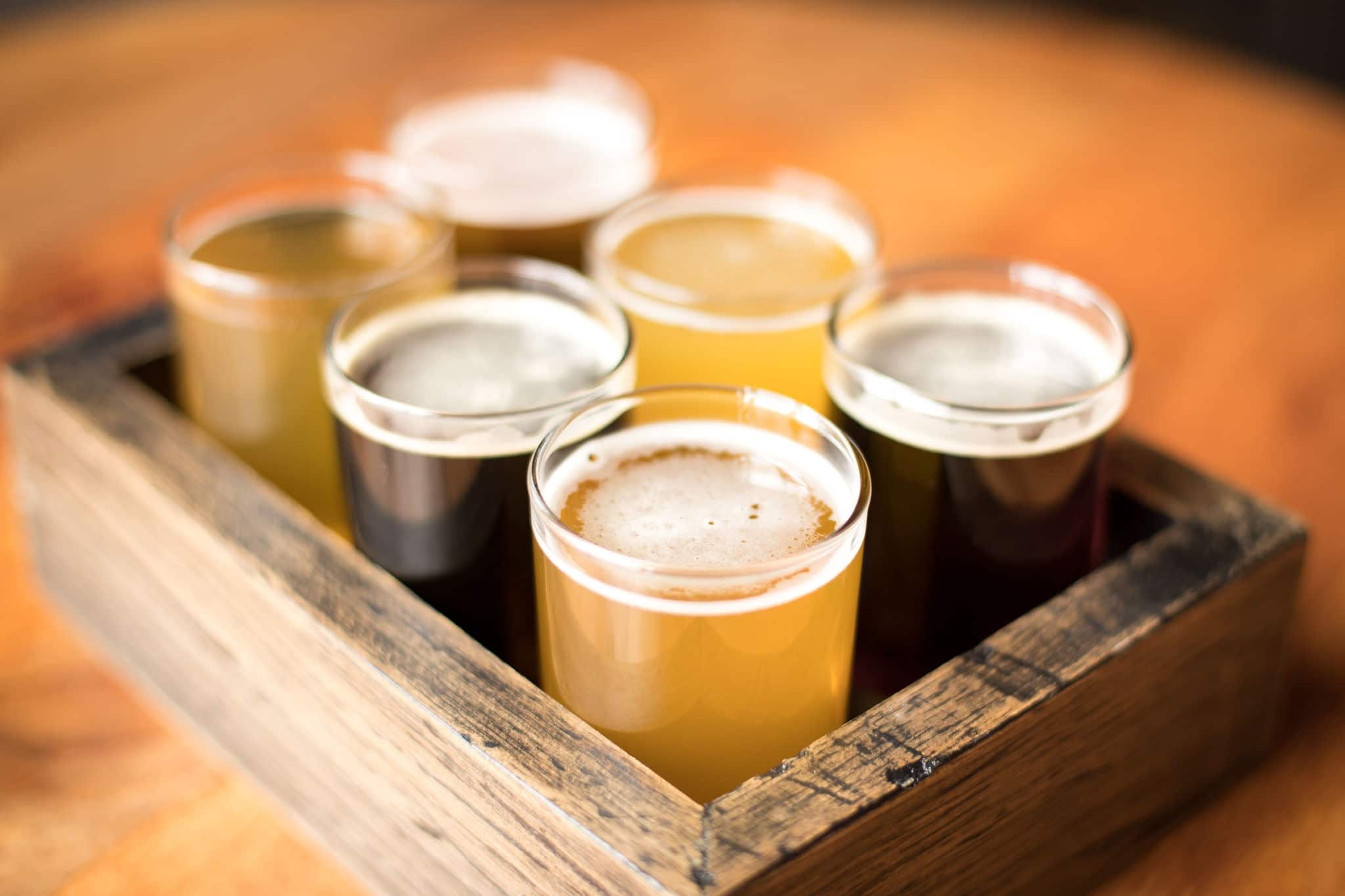 Close up on a flight of craft beers in a wood sampling tray at a local brewery