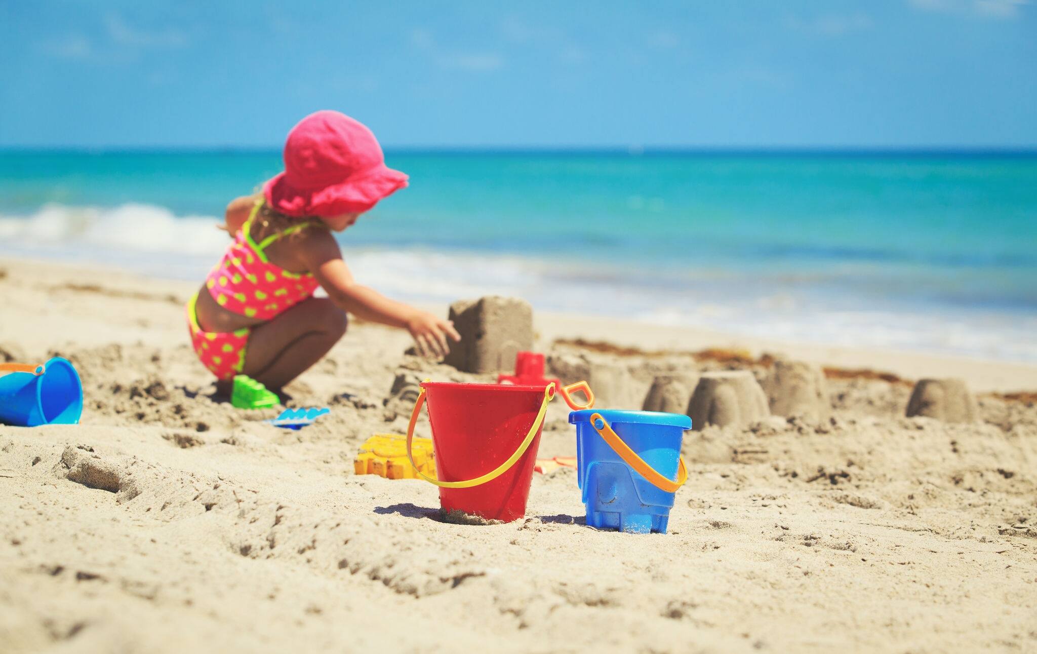 kids toys and little girl playing on the beach