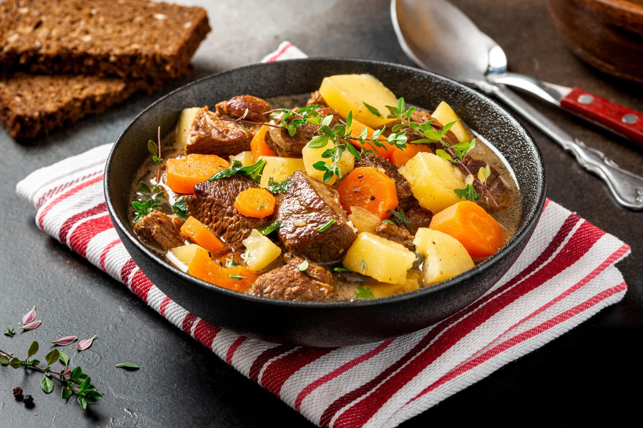 Traditional Irish stew in a black bowl on a dark background. Stew of lamb, potatoes, onions, carrots, and thyme. Traditional dish of St. Patrick's Day.