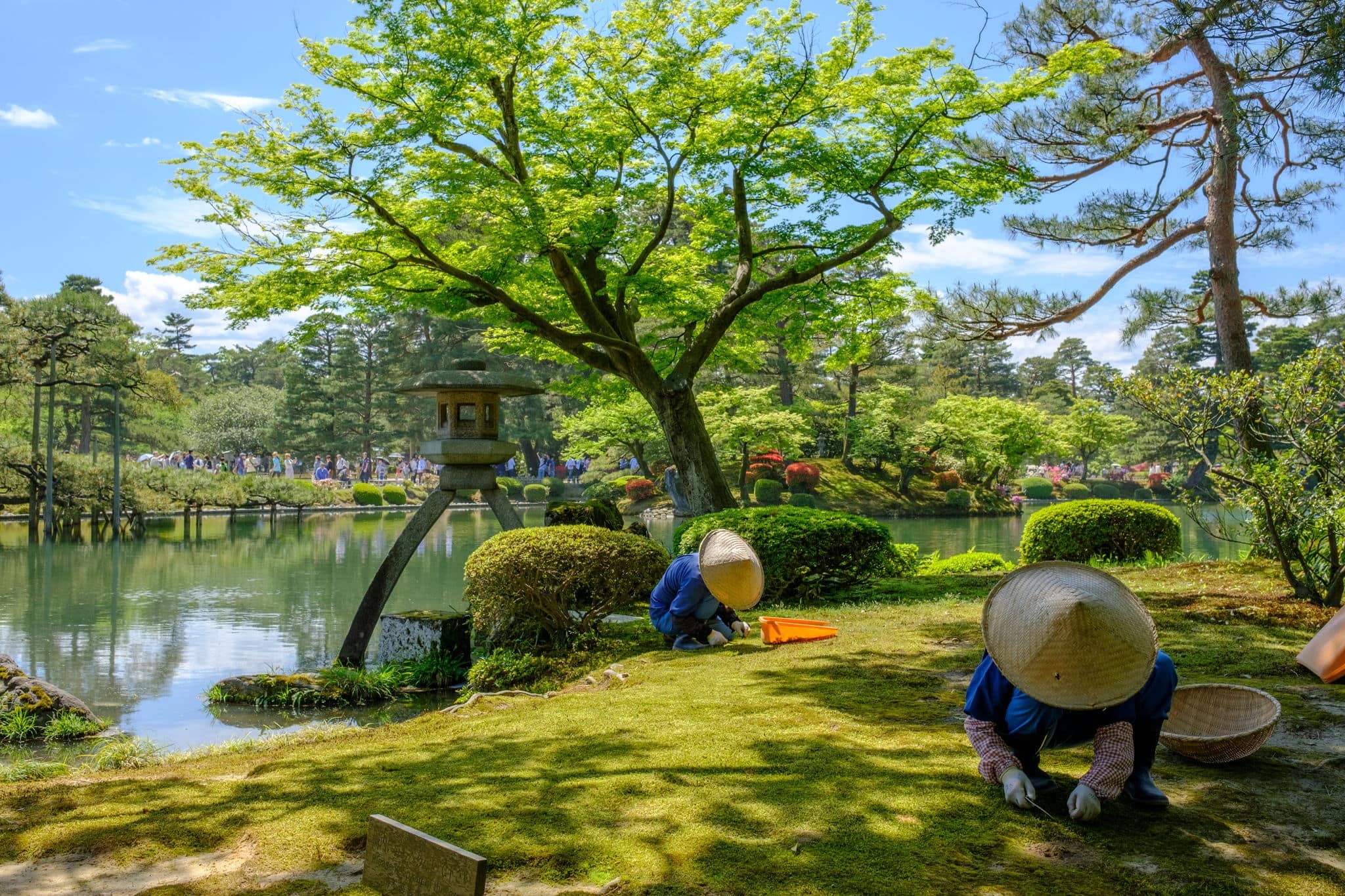 Japanese gardener near the Toro lantern in Kenrokuen, a japanese garden in Kanazawa, Ishikawa prefecture, Japan