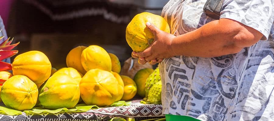 Street vendor selling yellow fruit at stand.
