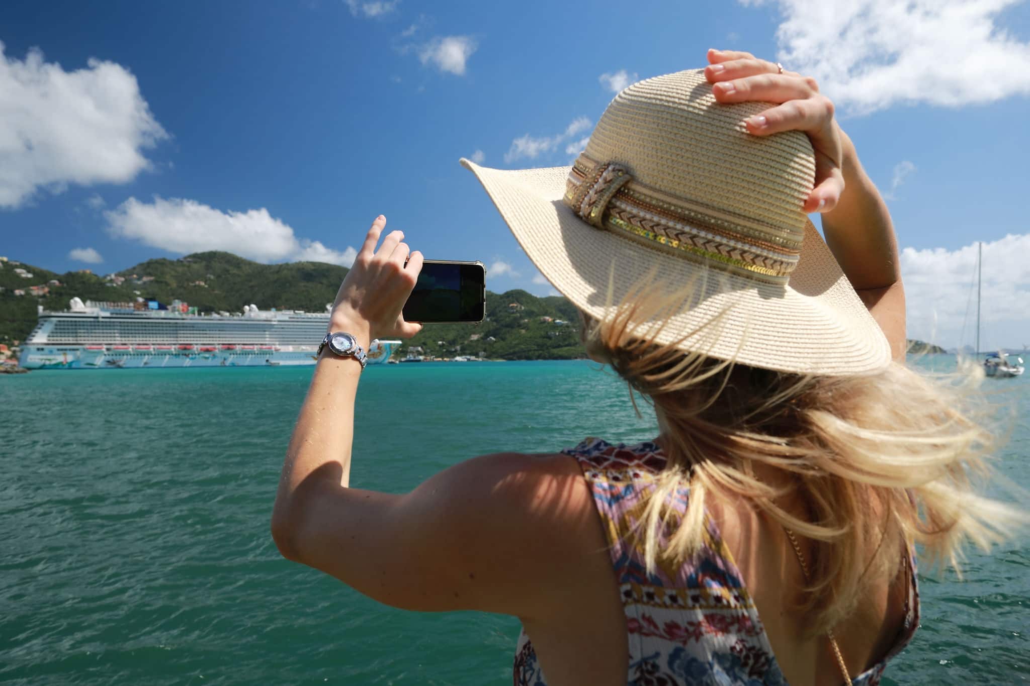 Beautiful woman in hat take picture from mobile phone of Luxury Cruise Liner hobart in the port in tropical island in summer time