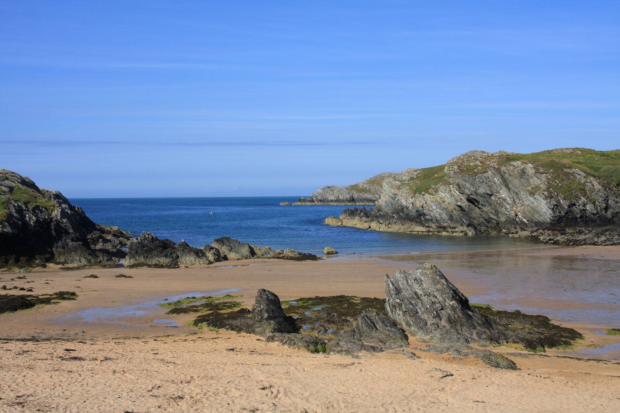 Porth Dafarch beach and cove with a fisherman going out on a kayak