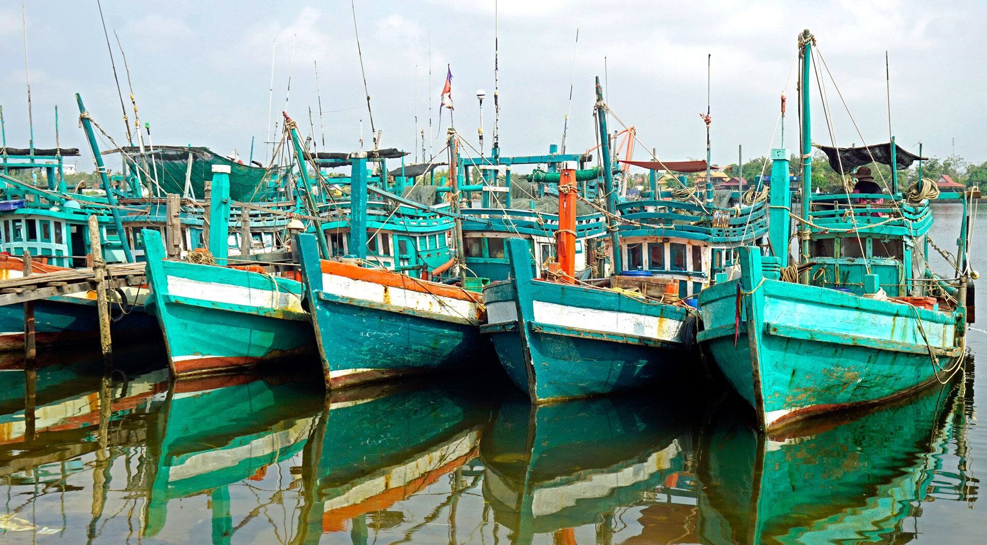 colorful wooden fisher boats in a harbor in Kampot in Cambodia