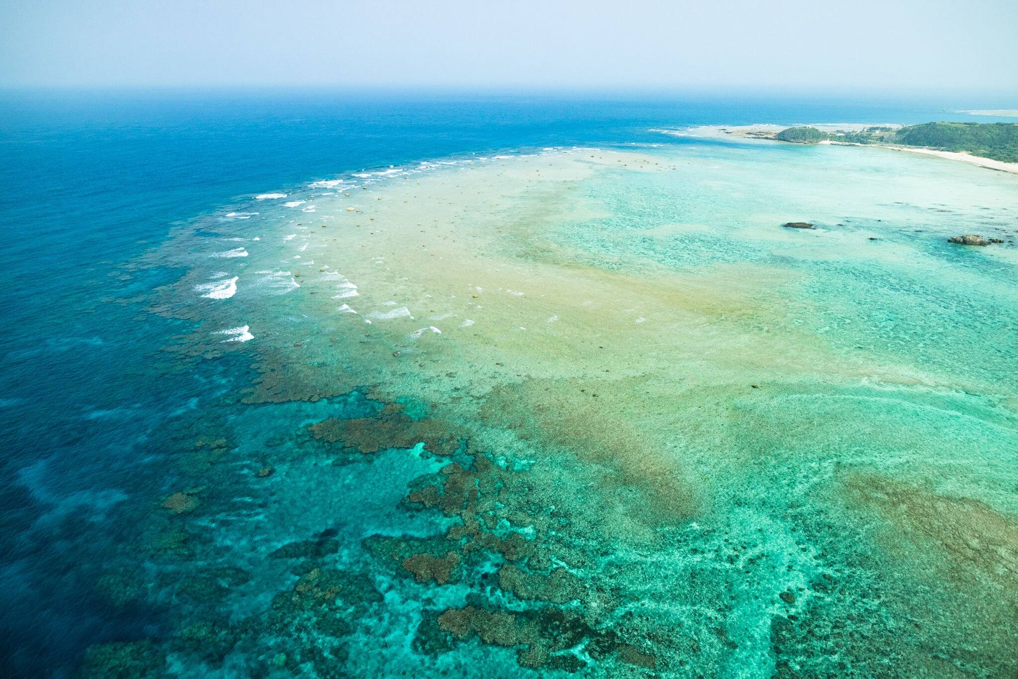 Aerial view of coral reef and clear blue tropical sea from paragliding flight, Amami Oshima Island, Kagoshima, Japan