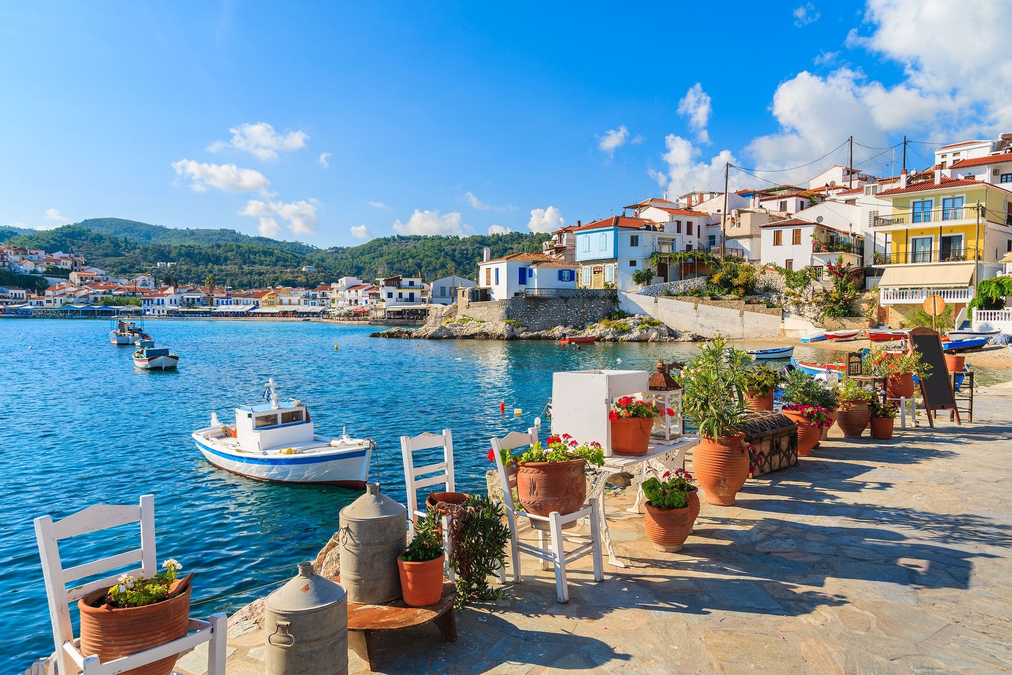 Flower pots on and view of fishing boats anchoring in Kokkari bay, Samos island, Greece
