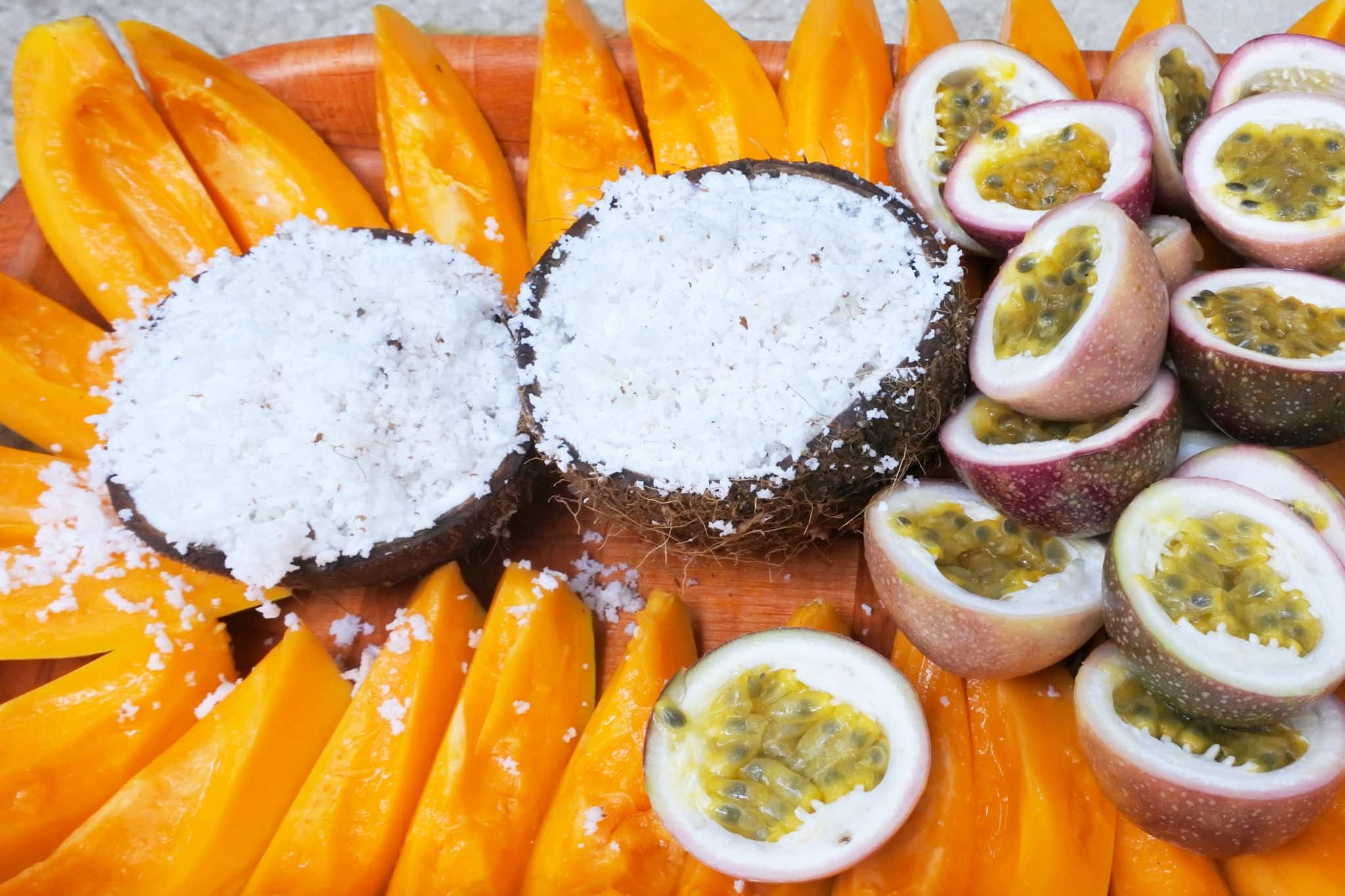 Fresh coconut, papaya and passion fruit served on a tray in Rarotonga, Cook Islands. Food background and texture.