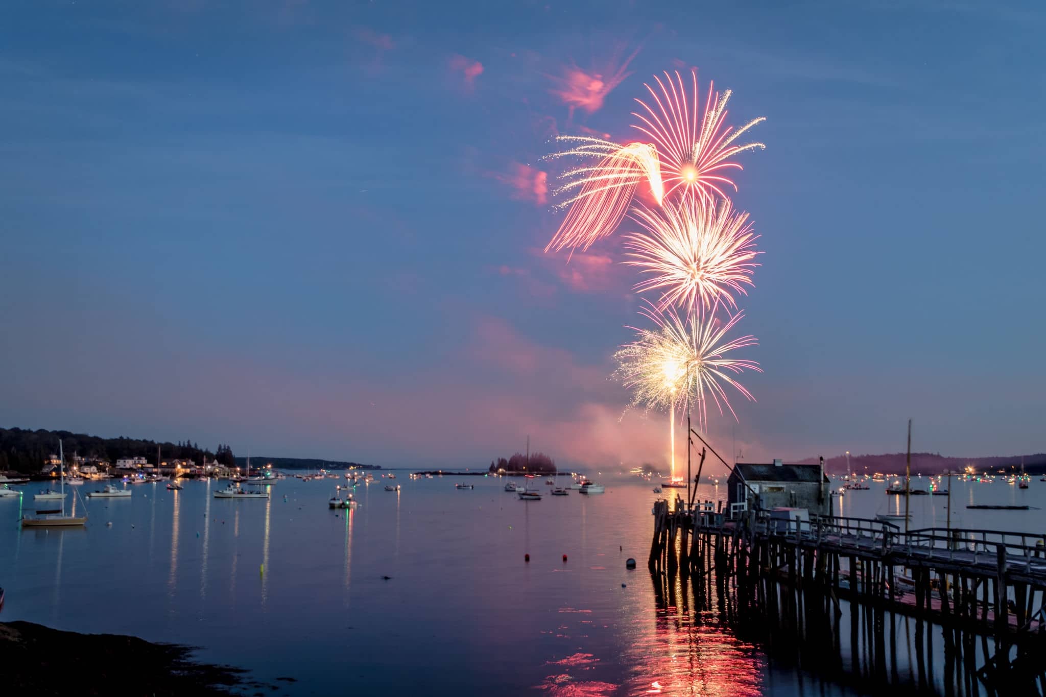 Fireworks over Boothbay Harbor, Maine, with reflections on the water during the July 4th Independence Day celebration.