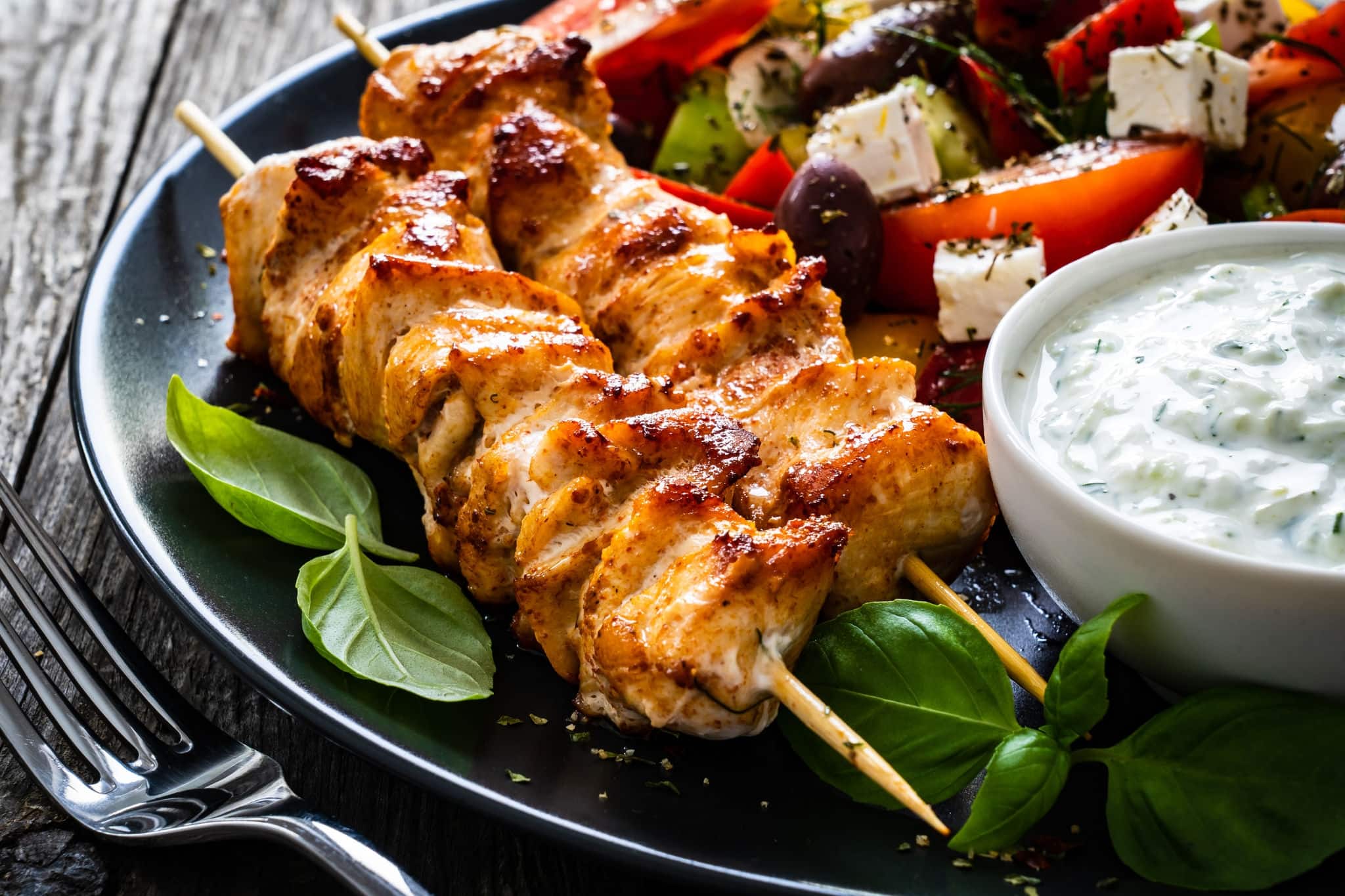 Fried souvlaki, greek salad and tzatziki on wooden table