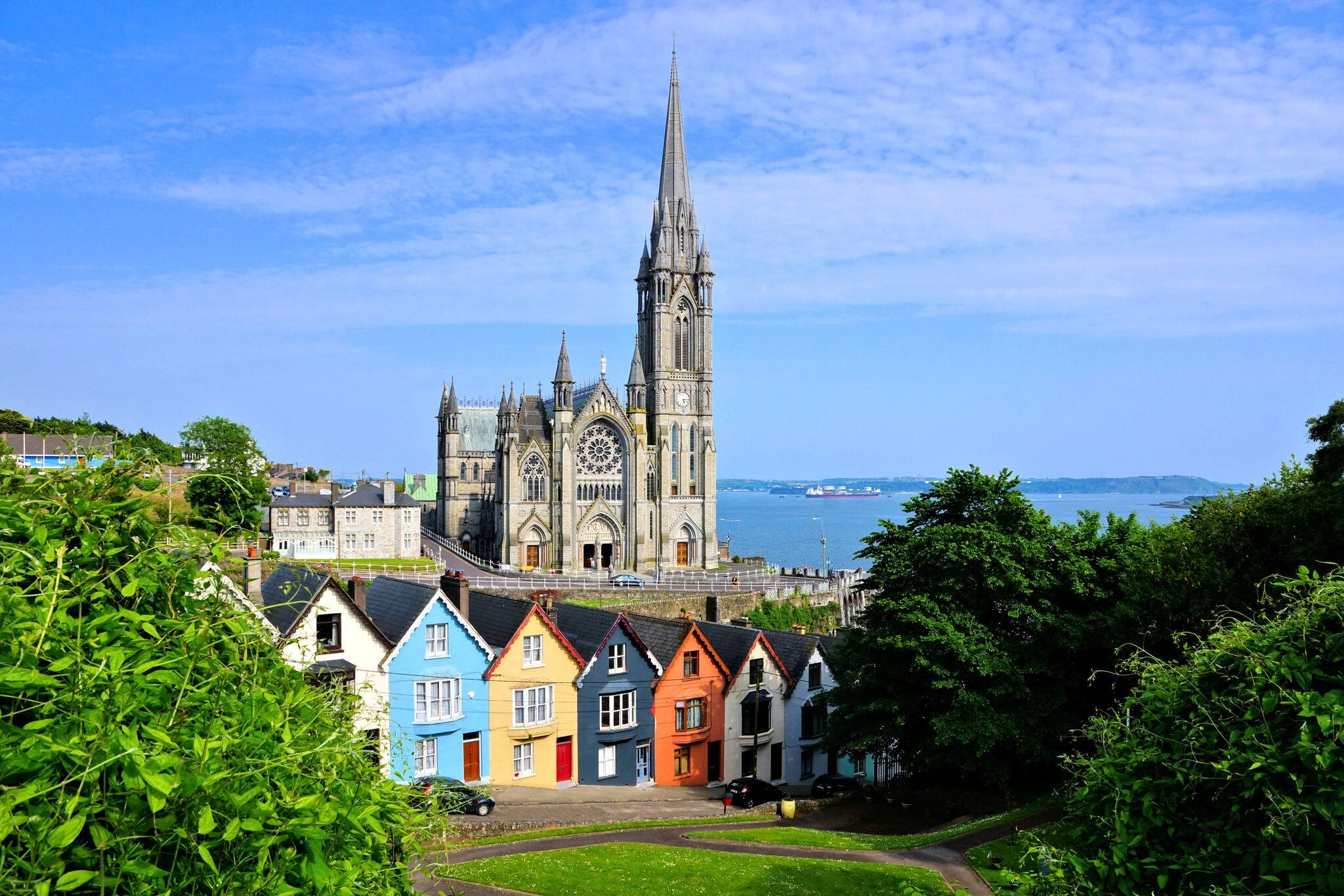 Colorful row houses with towering cathedral in background in the port town of Cobh, County Cork, Ireland