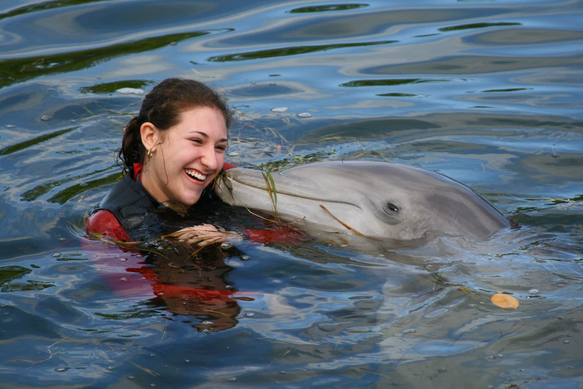 Smiling, attractive female teenager swimming with a dolphin