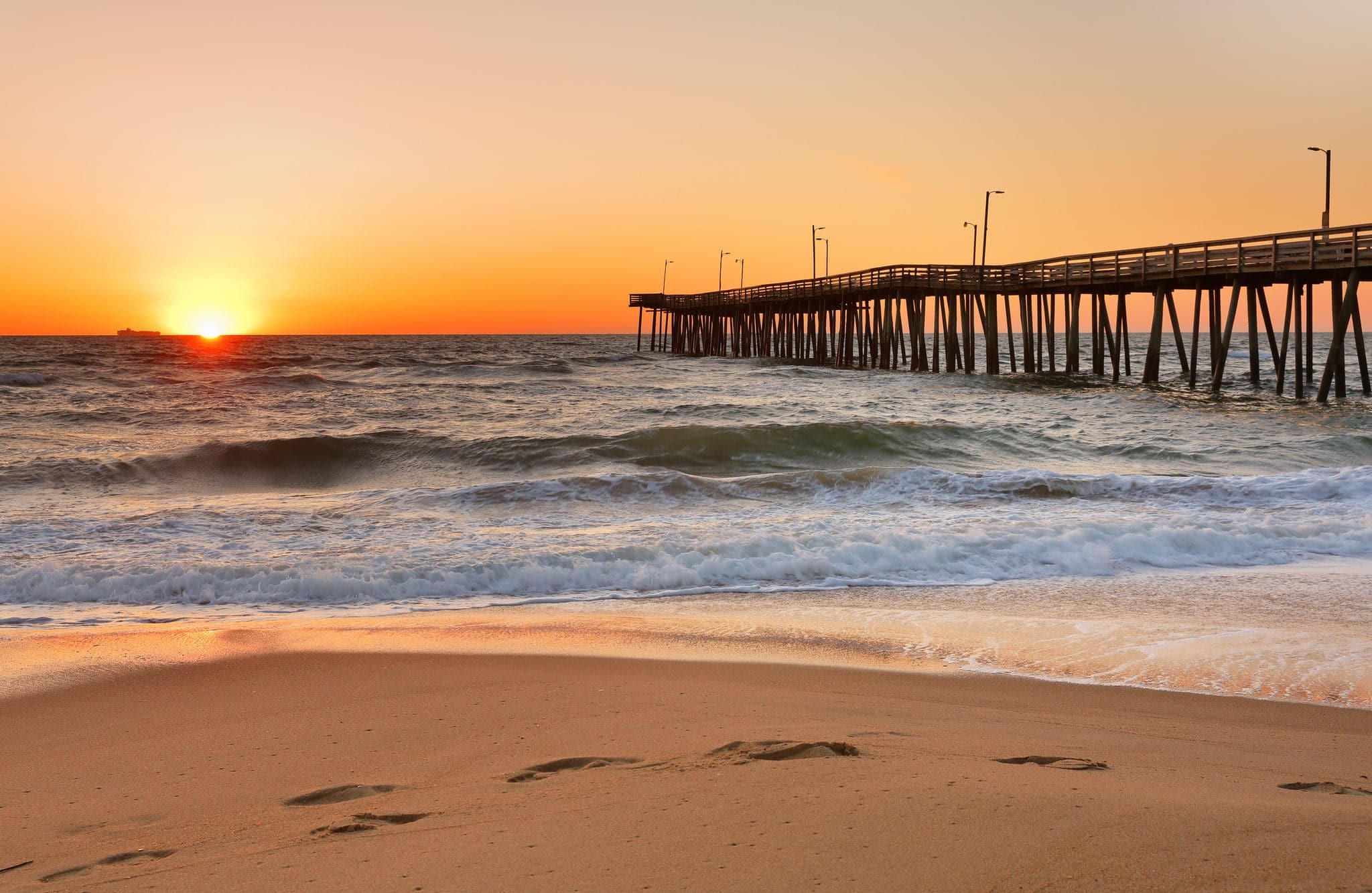 Fishing Pier at Sunrise at Virginia Beach, Virginia, USA. Virginia Beach, a coastal city in southeastern Virginia, lies where the Chesapeake Bay meets the Atlantic Ocean.