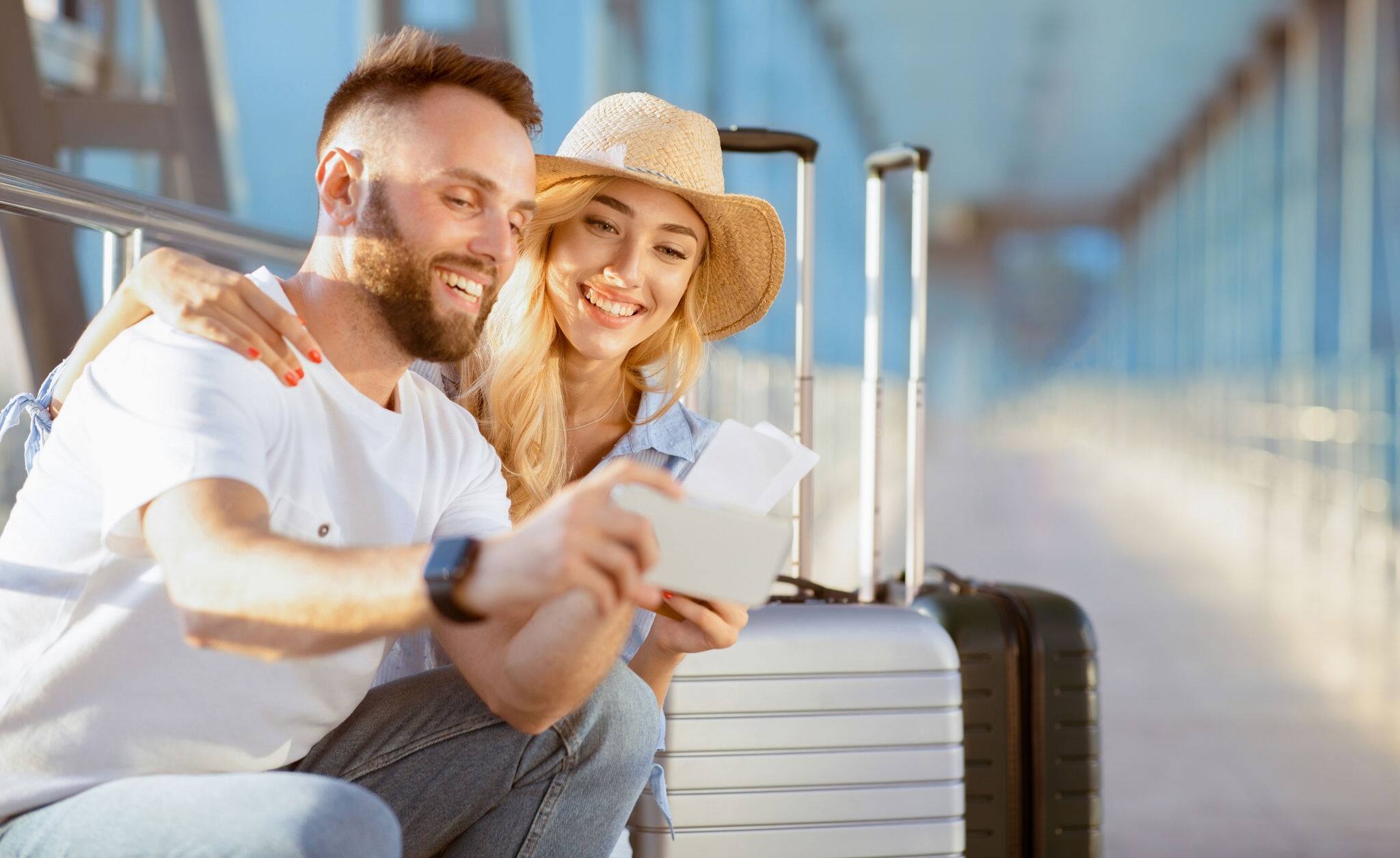Vacation Begins. Happy couple taking selfie with tickets, waiting for a flight in the airport building
