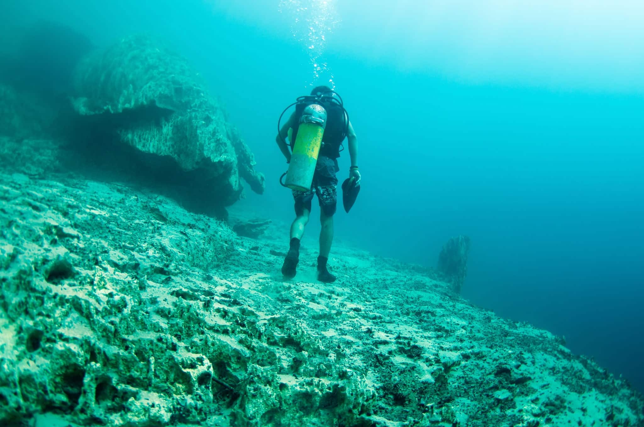 A diver walking underwater, below the hot spring, the different density of hot and cold water makes the vision blurry. Barracuda Lake, Coron, Philippines.
