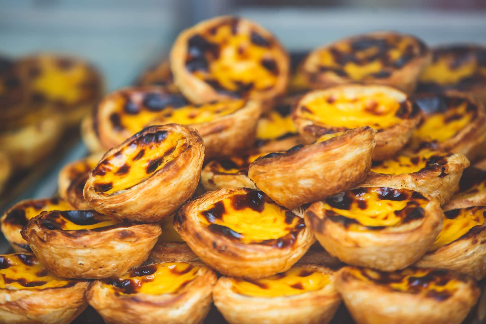 Traditional Portuguese egg tart pasty cakes, dessert Pasteis de nata with different portuguese pastry on the cafe store window, pastel de nata