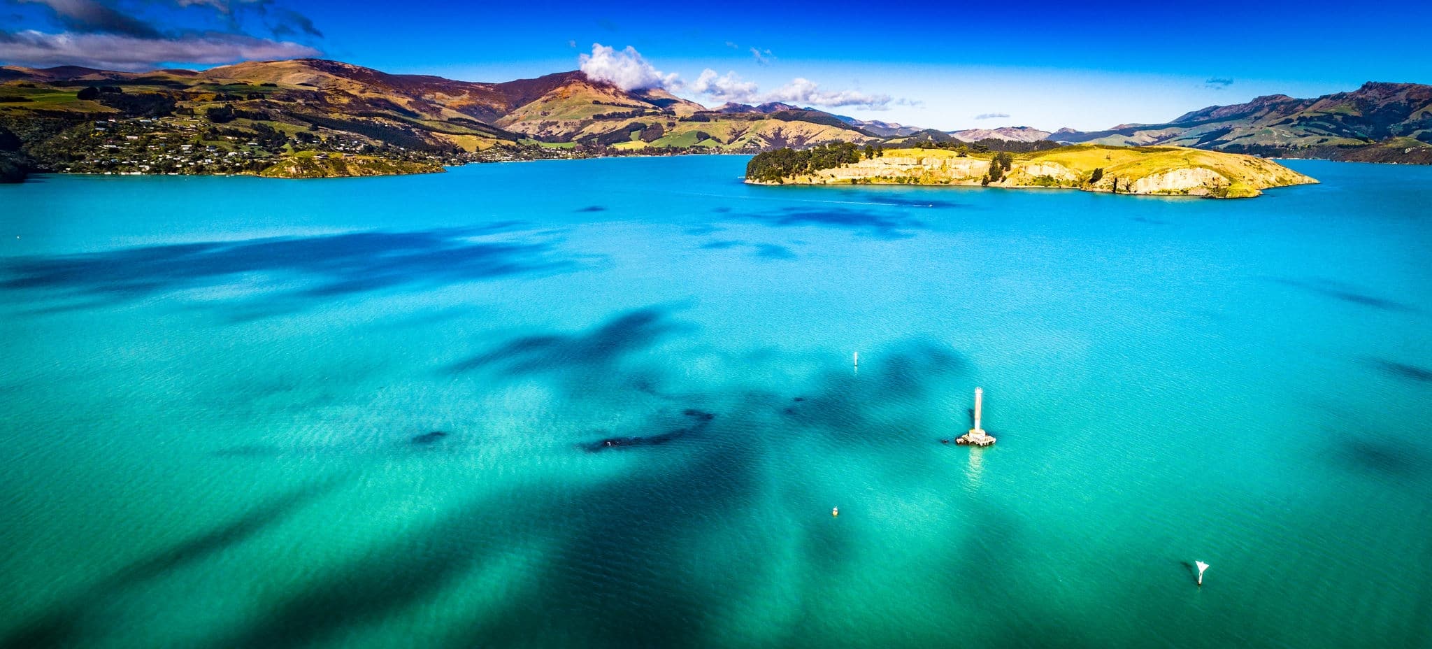 Spectacular aerial view of a Lyttelton Harbour surrounded by multiple native trees and forest showcasing a deep blue ocean located in the Canterbury Region of the South Island NZ