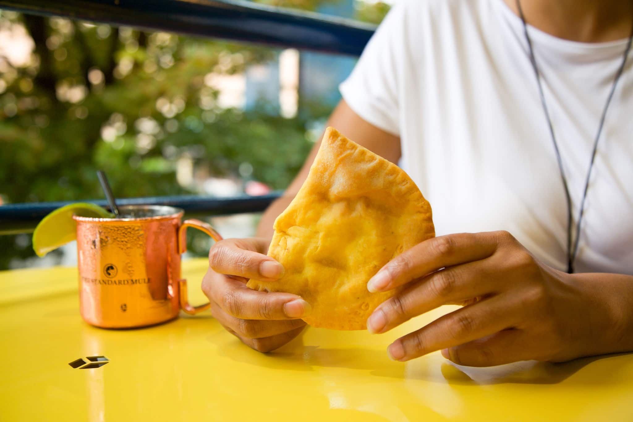 A person enjoying a Jamaican patty on the patio on a sunny day