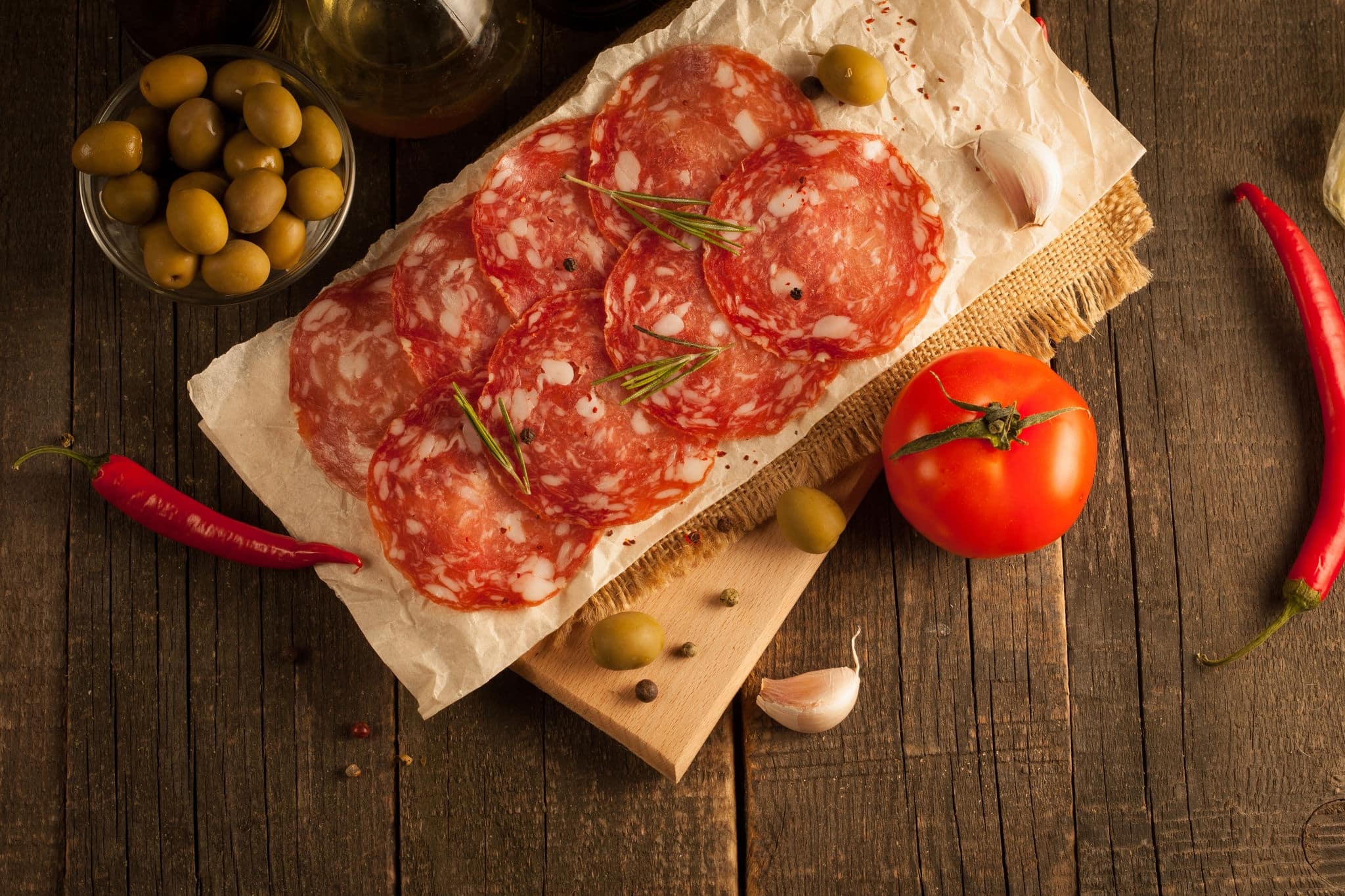 Chorizo sausage and salami, thin cut. spanish salami on the wood background with spices, paprika, pepper. Spicy food. Garlic, tomato, salad background.