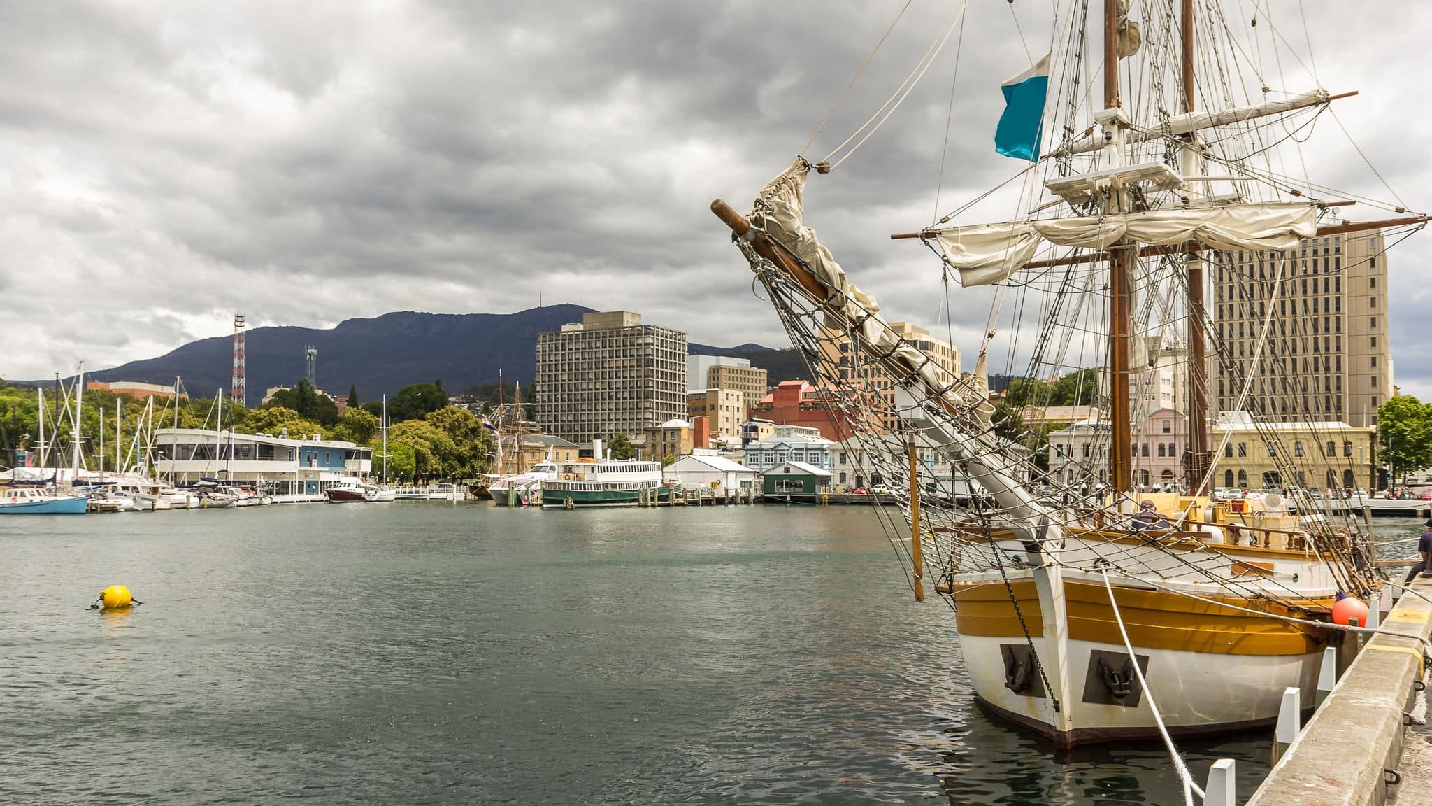 Yacht Tour Boat at Wharf in Hobart Harbour with Kunanyi Mount Wellington background under Dramatic Sky, Derwent River, Hobart, Tasmania