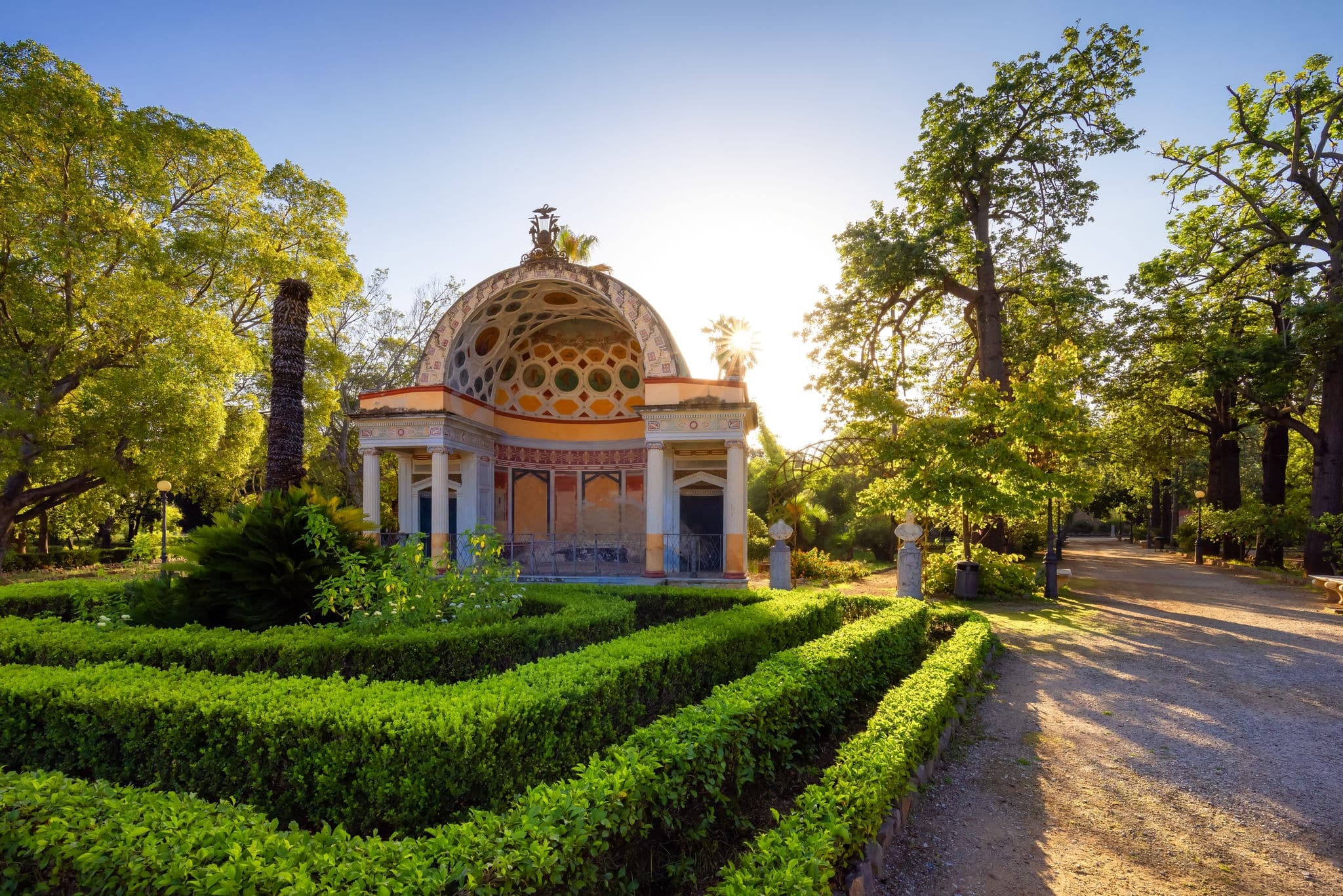 Path with vibrant green trees in city park, Villa Giulia. Palermo, Sicily, Italy.
