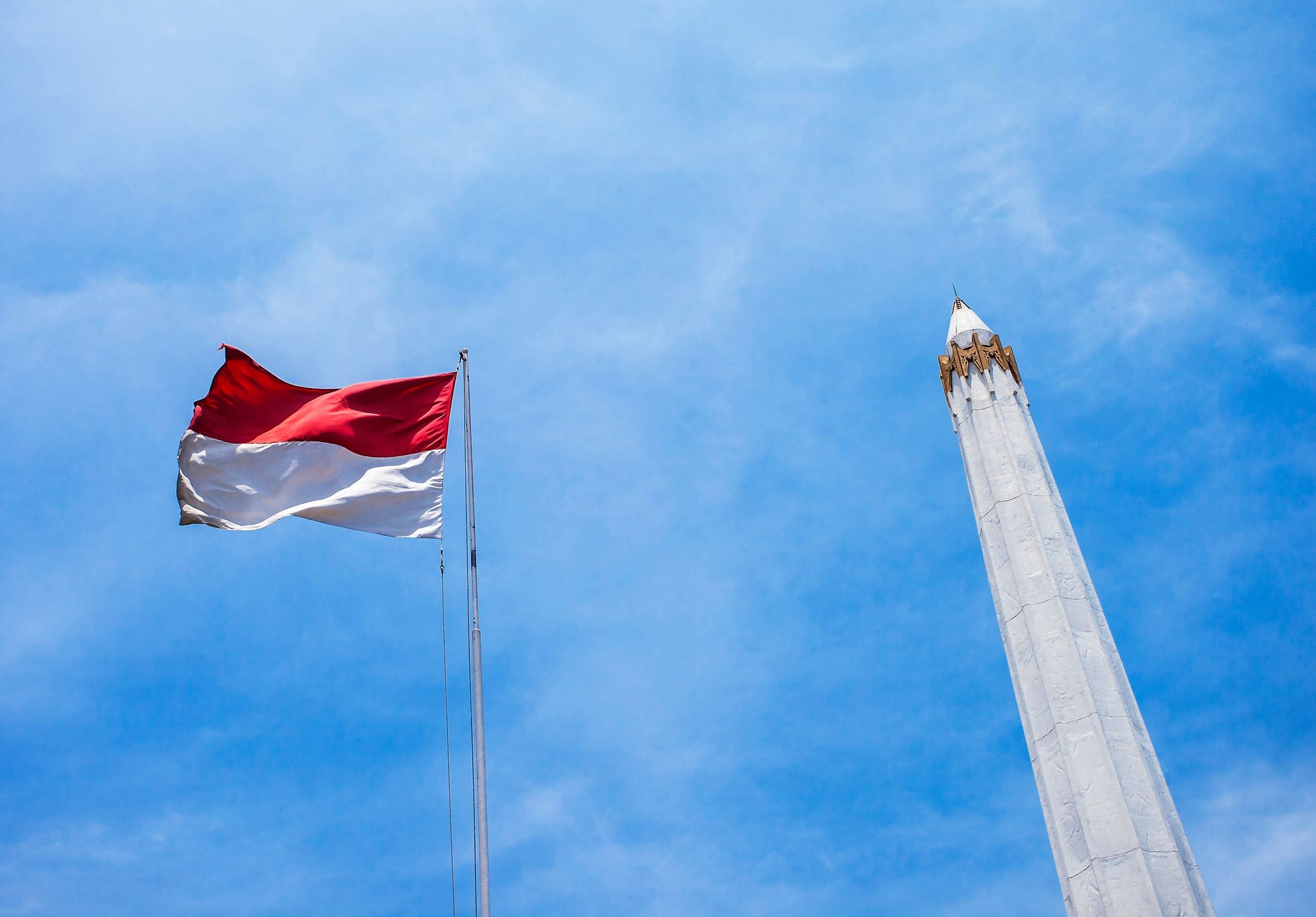 Indonesian flag and the heroes monument in the blue sky, Heroes monument located in Surabaya, East Java.