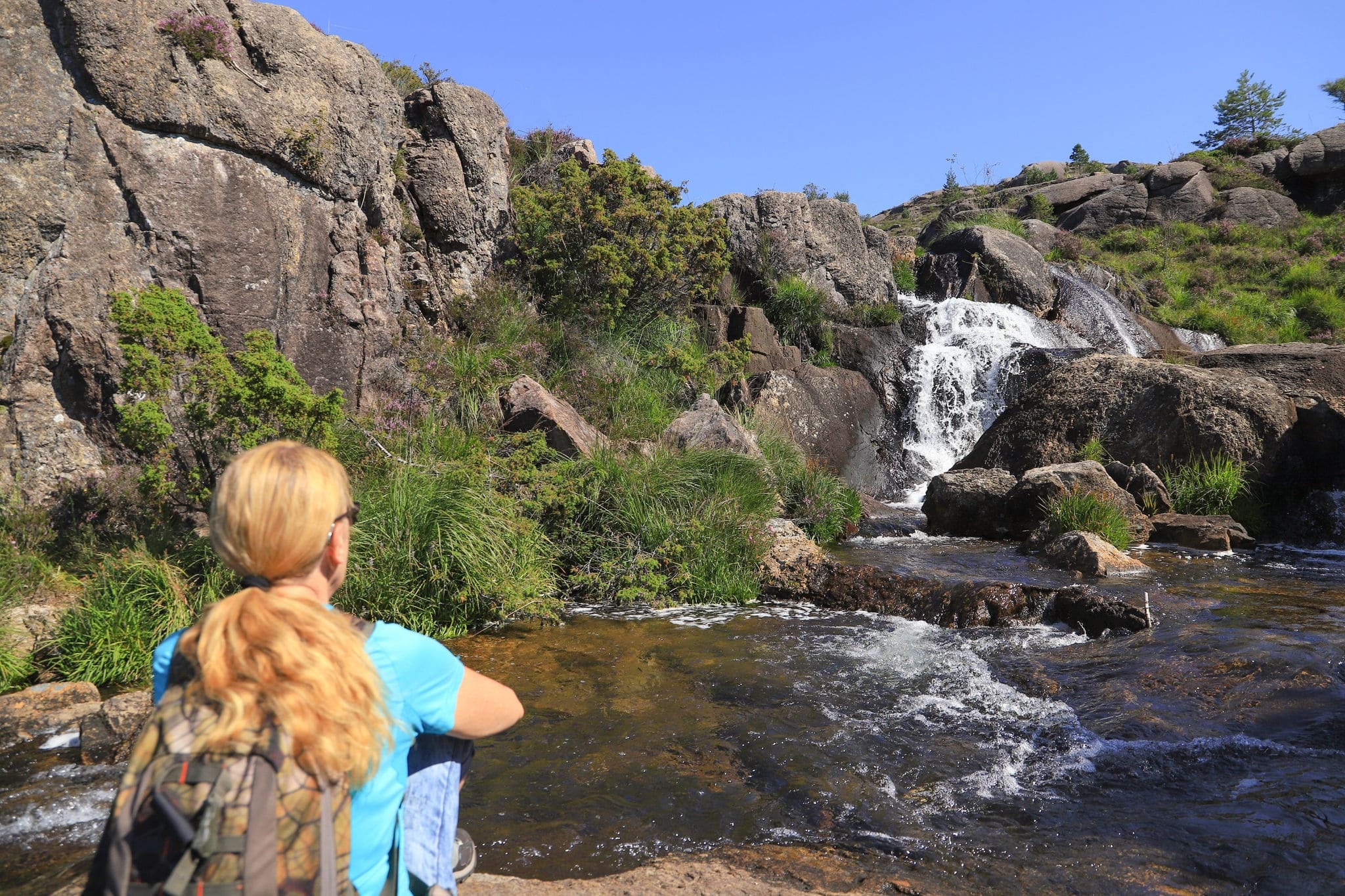 A woman is watching the waterfall along the hiking trail to Trollpikken mountain in Magma UNESCO Global Geopark, south Norway