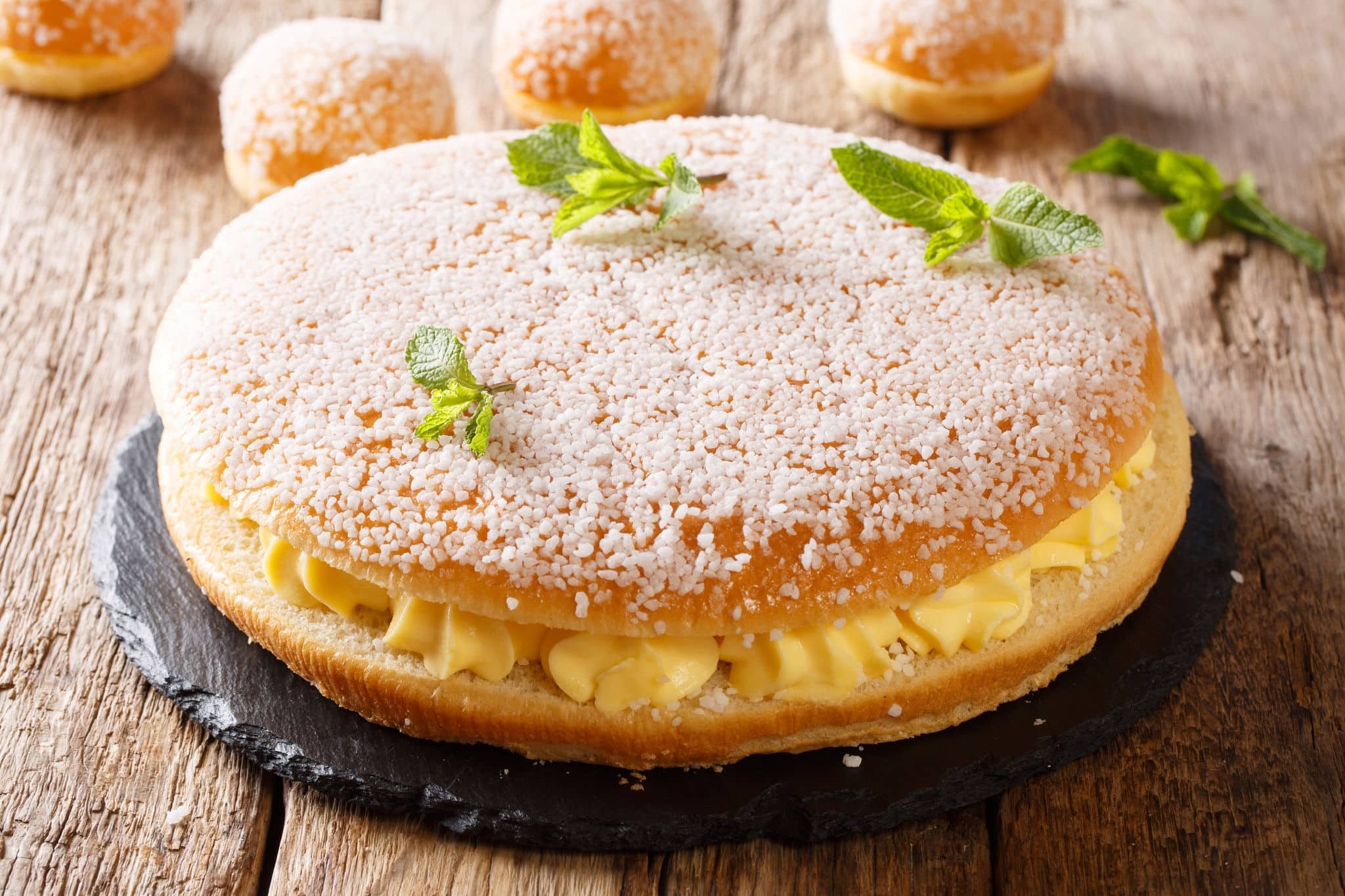 French tropezienne tarte brioche cake with tender cream and pearl sugar close-up on the table. horizontal
