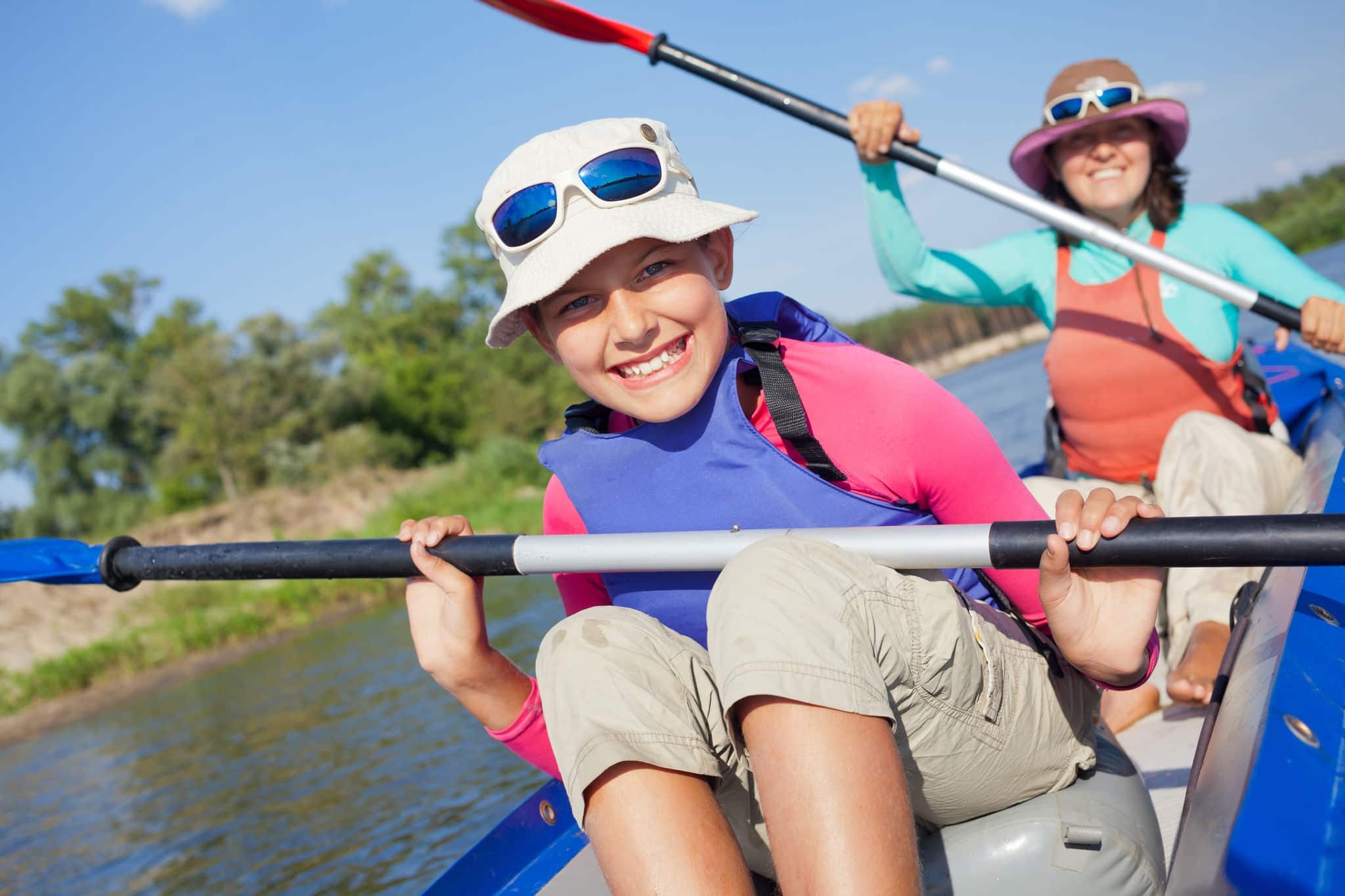 Summer vacation - Cute girl with mother kayaking on river. 