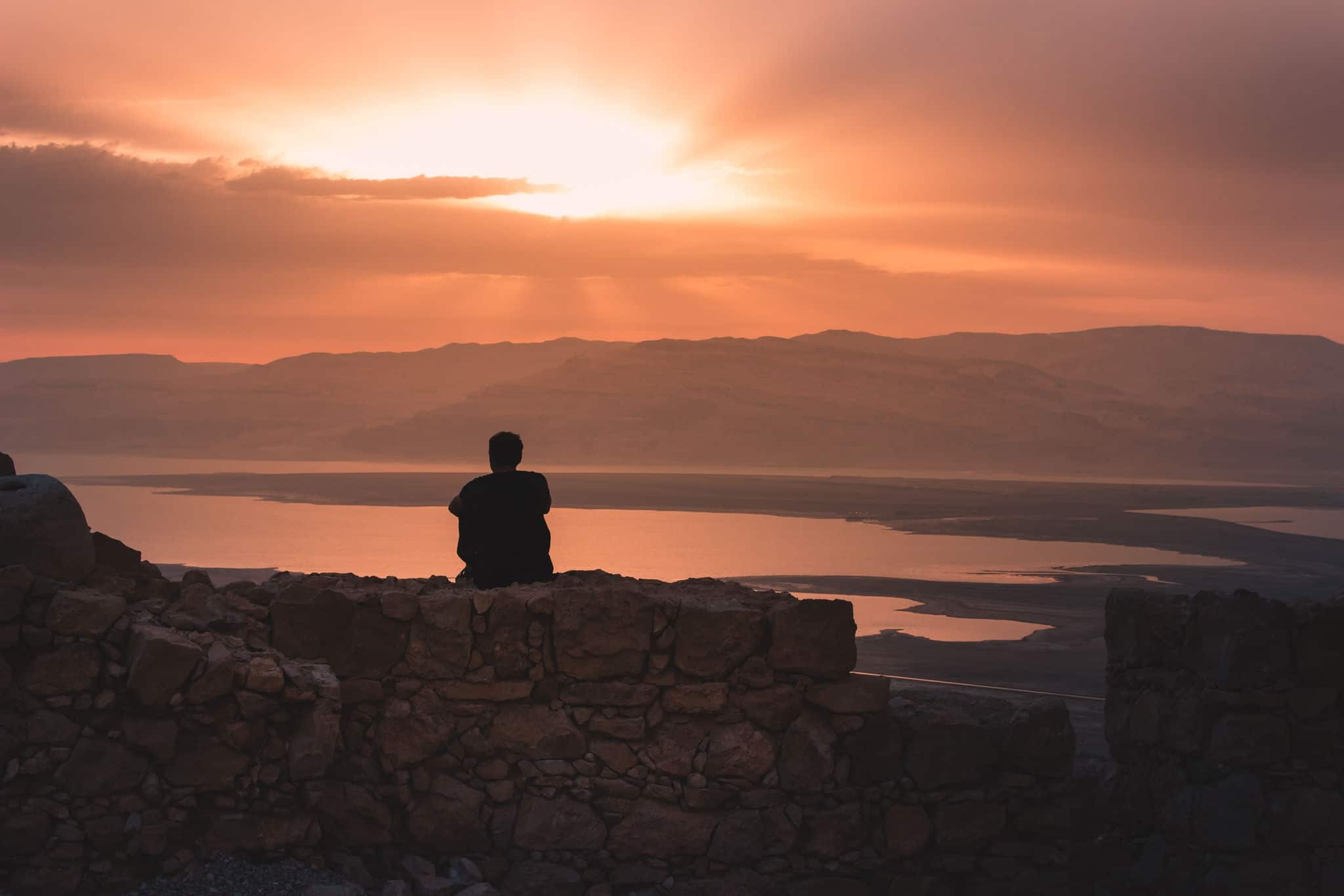 Man looking at sunrise from Masada with view on the dead sea in Israel