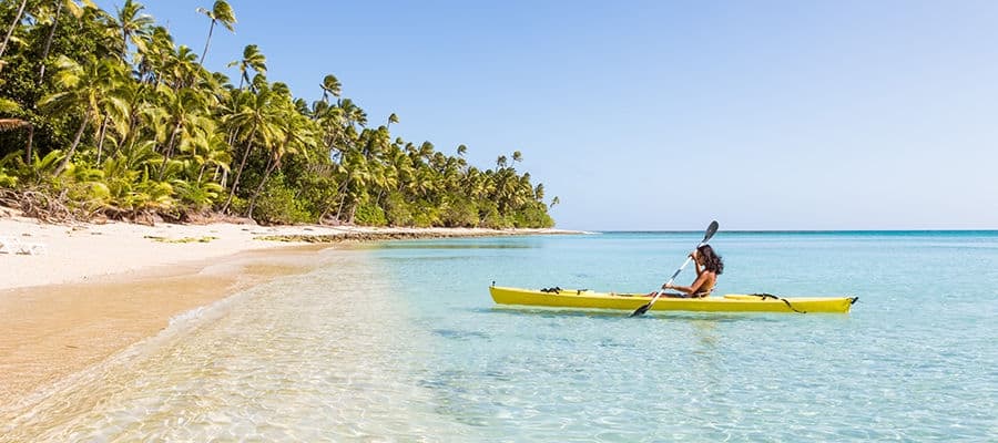 Woman kayaking towards beach shore in Savusavu, Fiji.