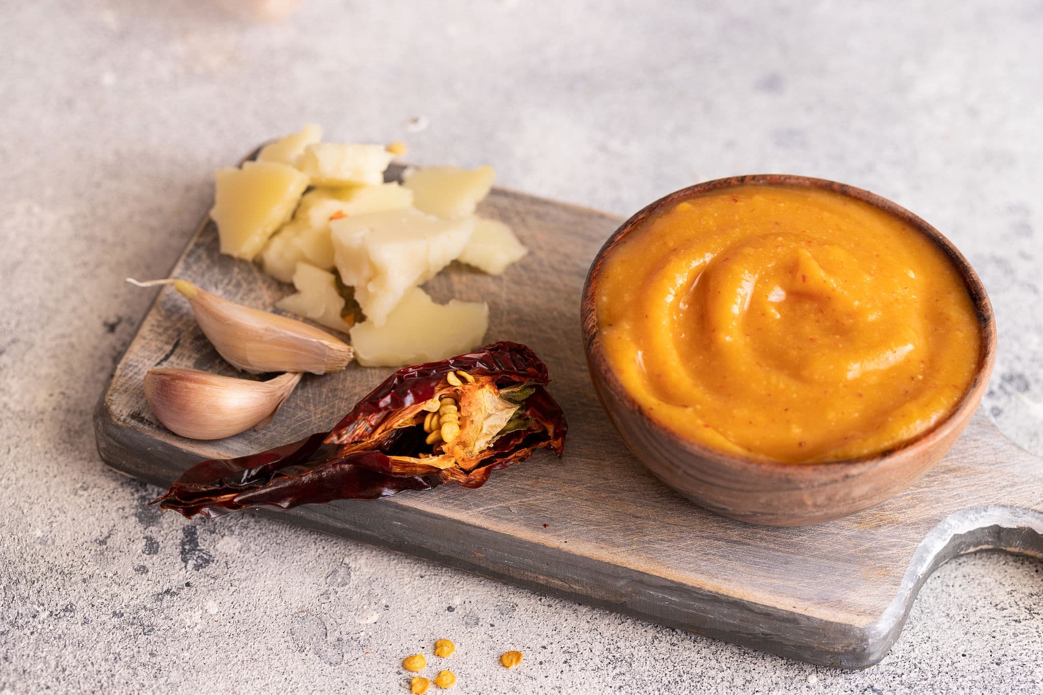 Almogrote , cheese paste form La Gomera, Canary Islands in wooden bowl on cut board with hard goat cheese, peppers  and garlic.Close up