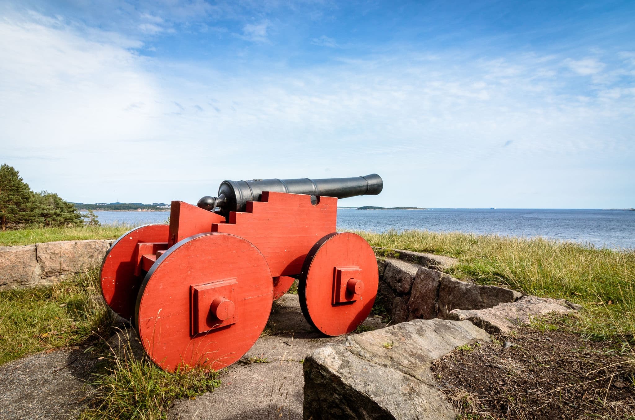 Red cannon standing at Odderoya, Kristiansand, Norway. View to the sea, blue sky