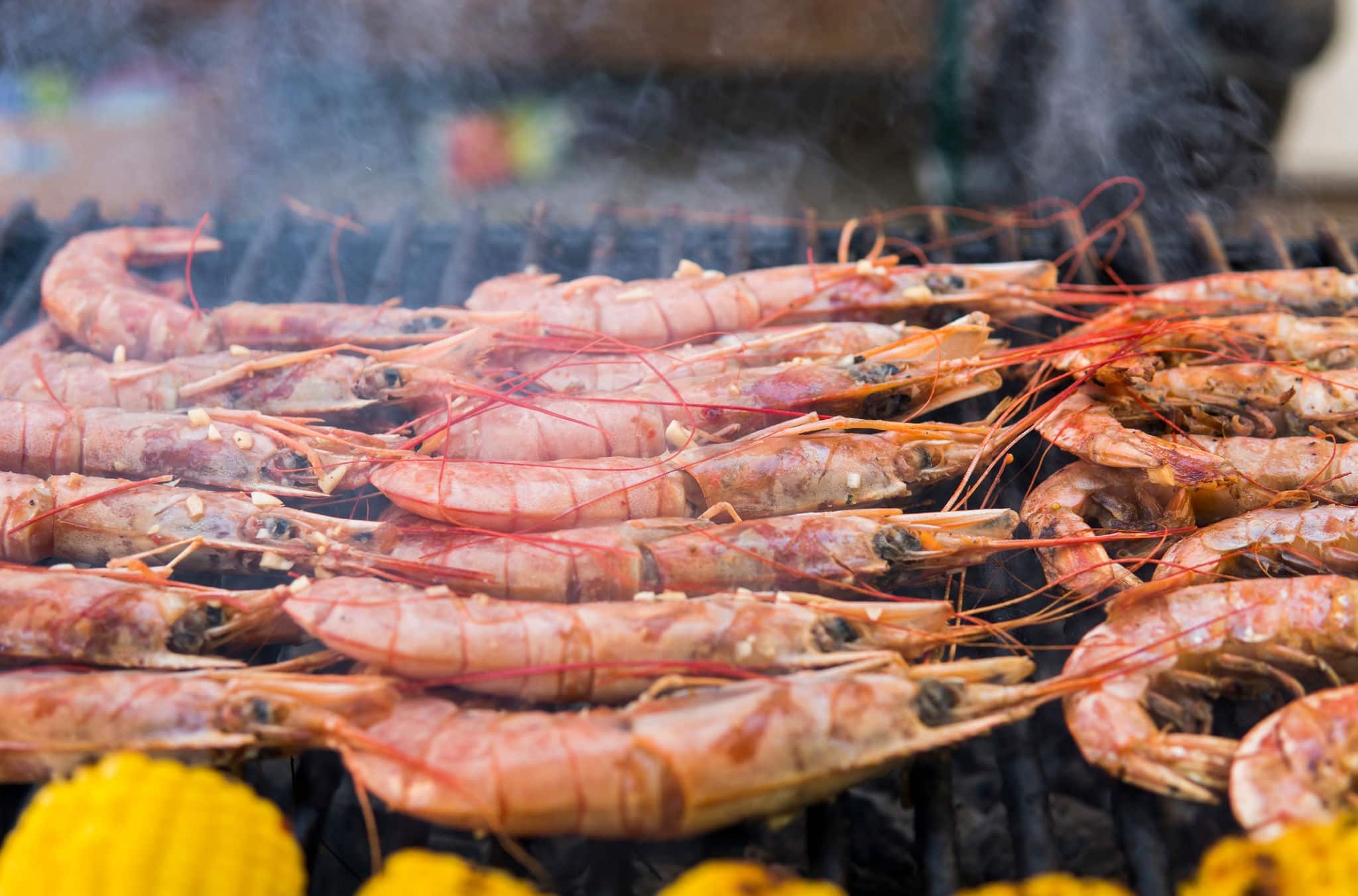 Appetizing grilled shrimps and corn on a food fest. Sea food and vegetables.