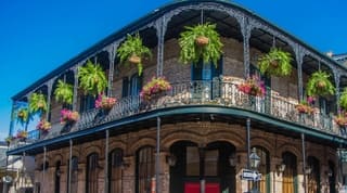French Quarter architecture in New Orleans, Louisiana. House in French Quarter in 18th century Spanish style with cast iron galleries with hanging plants and pastel colors. 