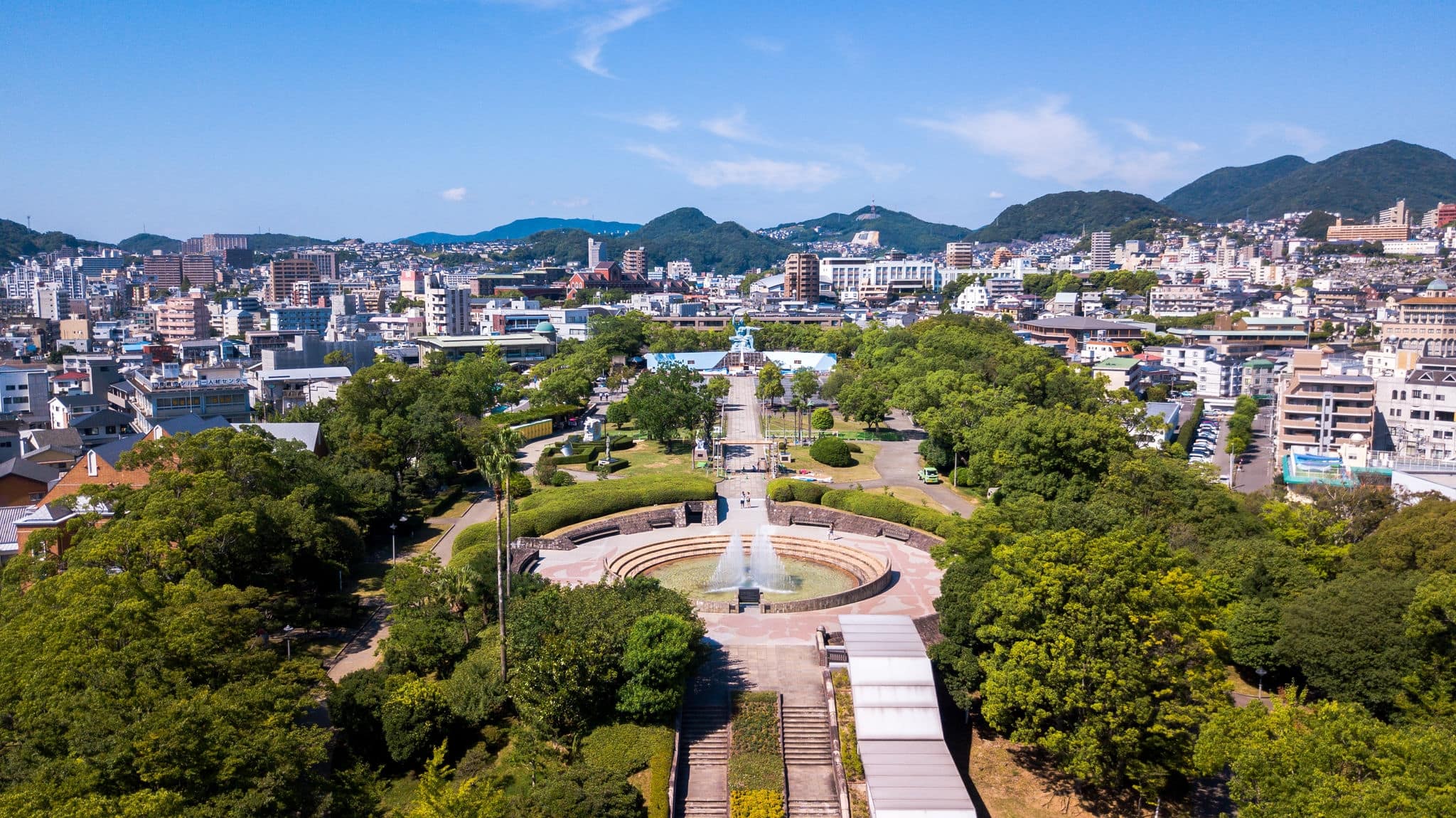 High angle view of Nagasaki Peace park in Japan. Scenery consist of statue, many building, blue sky with cloud and green tree.