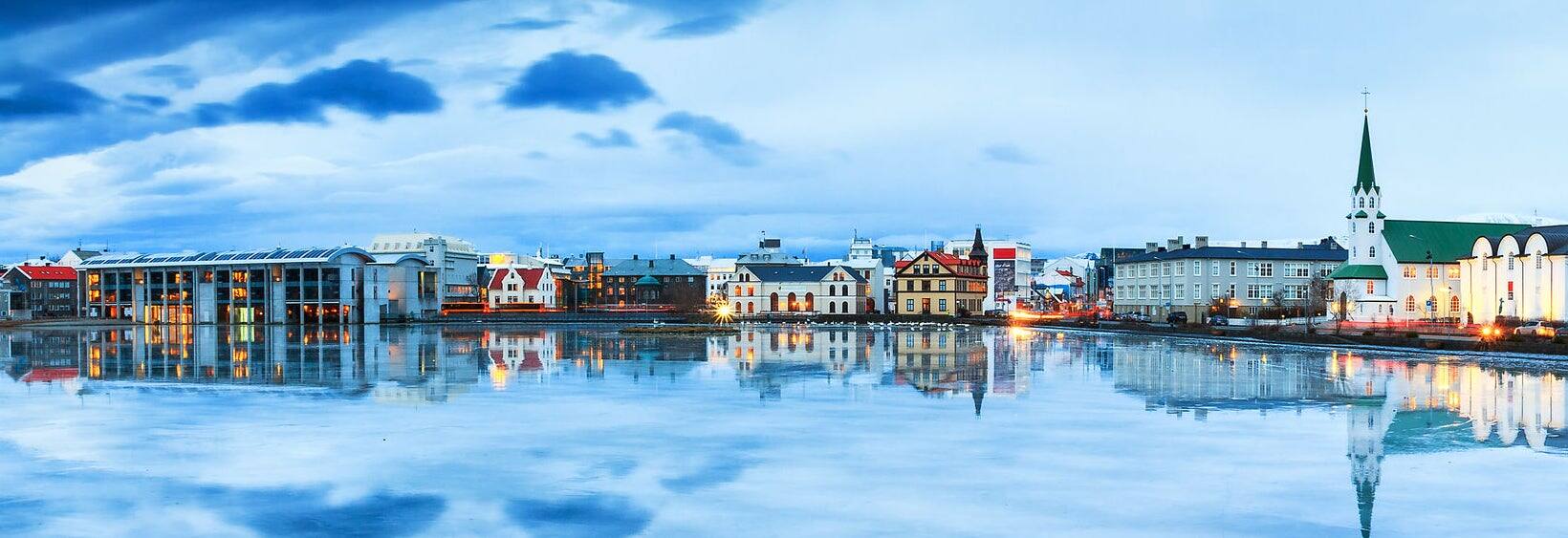 Beautiful panorama of the skyline cityscape of Reykjavik, reflected in lake Tjornin at the blue hour in winter