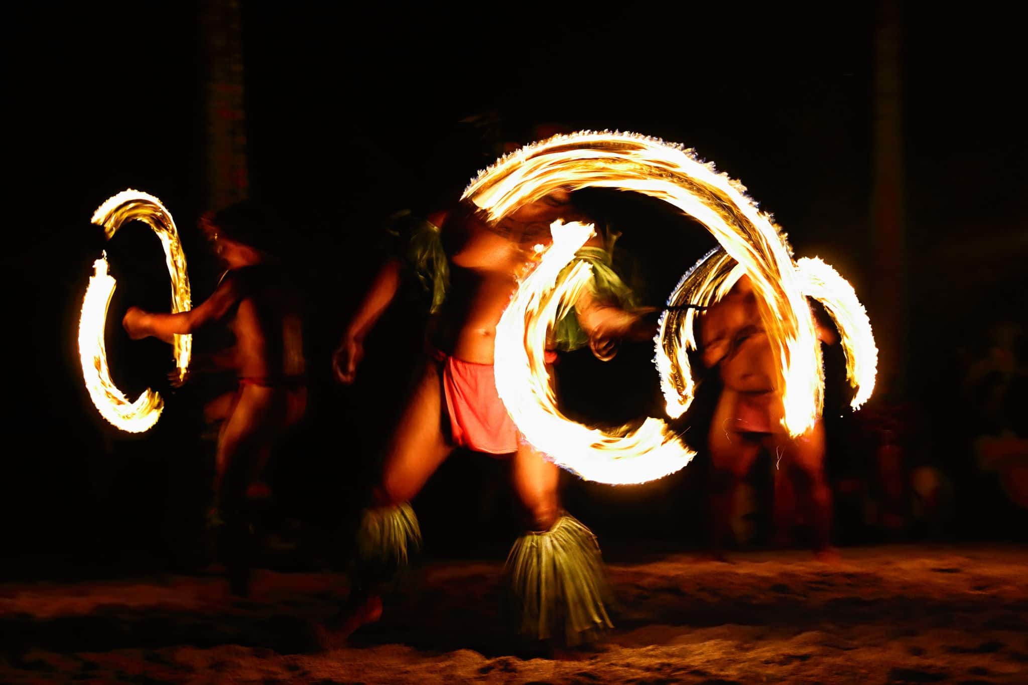 Fire dancers at Hawaii luau show, polynesian hula dance men juggling with fire torches.