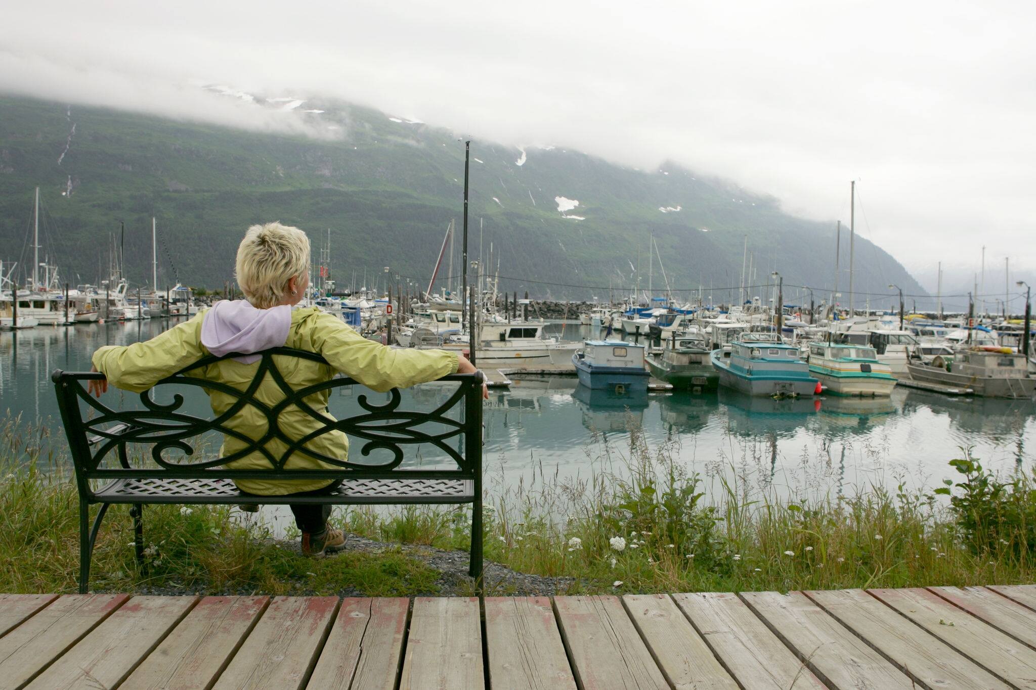 Blond woman sitting on bench at Whittier harbor, Alaska