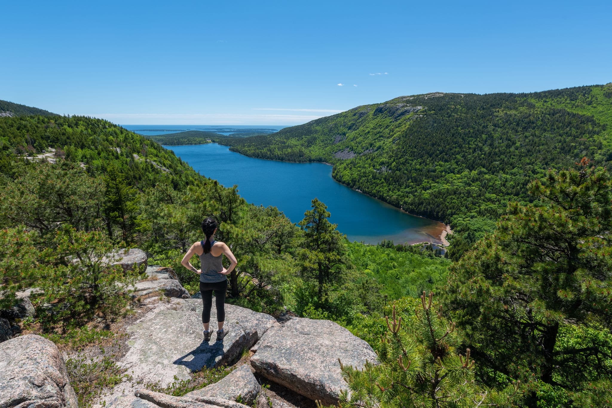 Female hiker reaching the top of an overlook of Jordan Pond at Acadia National Park 
