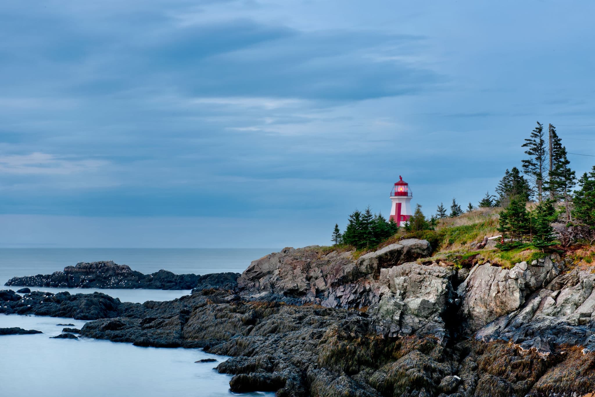 The Head Harbour Lightstation shines brightly on a gloomy morning at low tide. Also known as the East Quoddy Head. Campobello Island, New Brunswick, Canada.
