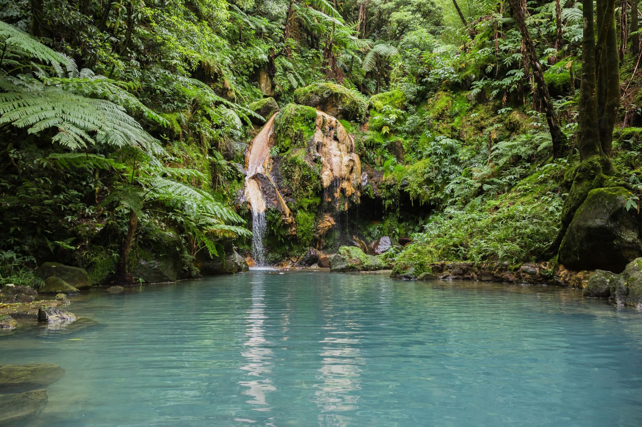 Blue lagoon of natural hot spring at "Caldeira Velha" where people swim in warm water in Sao Miguel island, Azores, Portugal