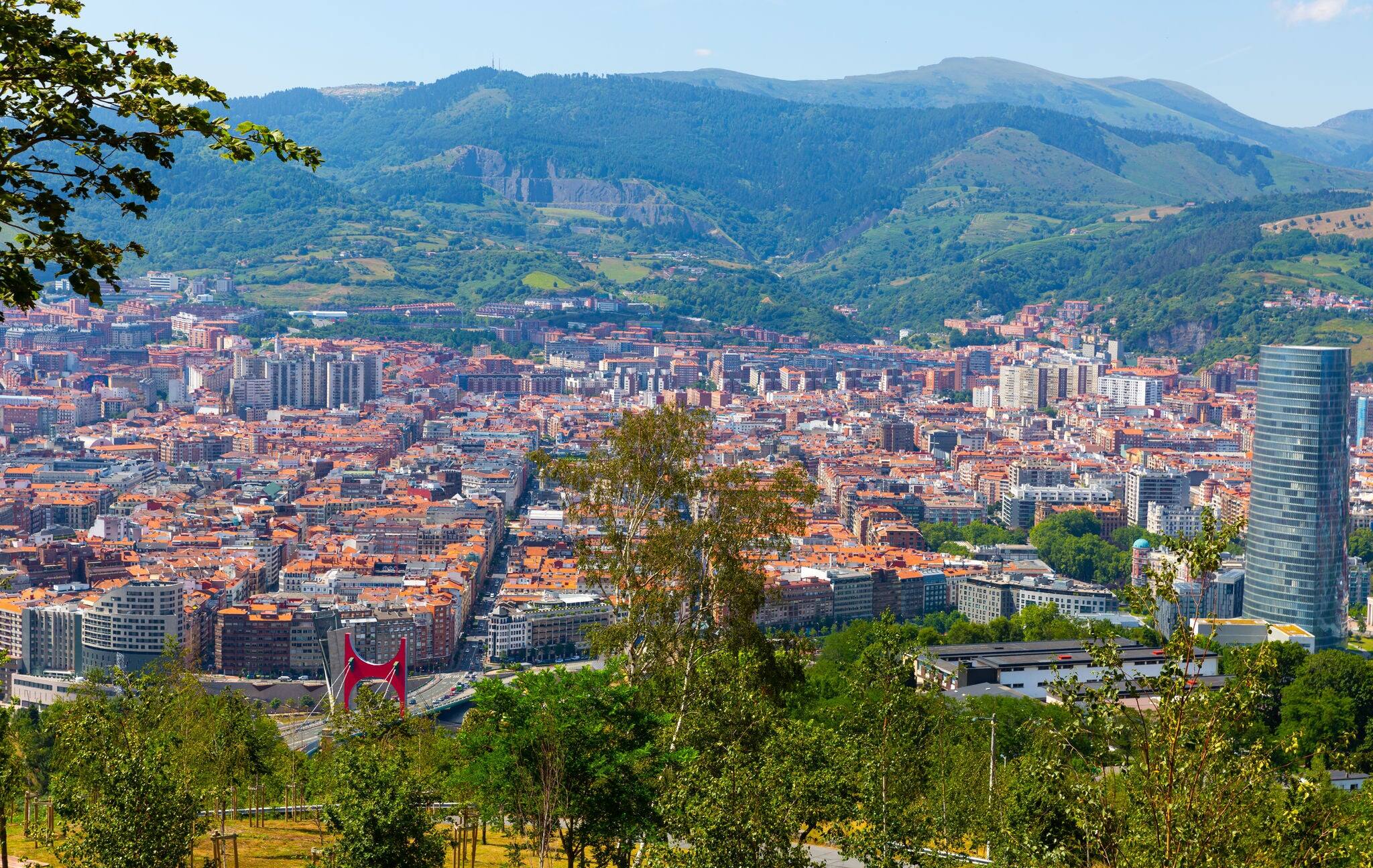 Scenic panoramic view of modern Bilbao cityscape surrounded by mountain ranges in summer, Spain 