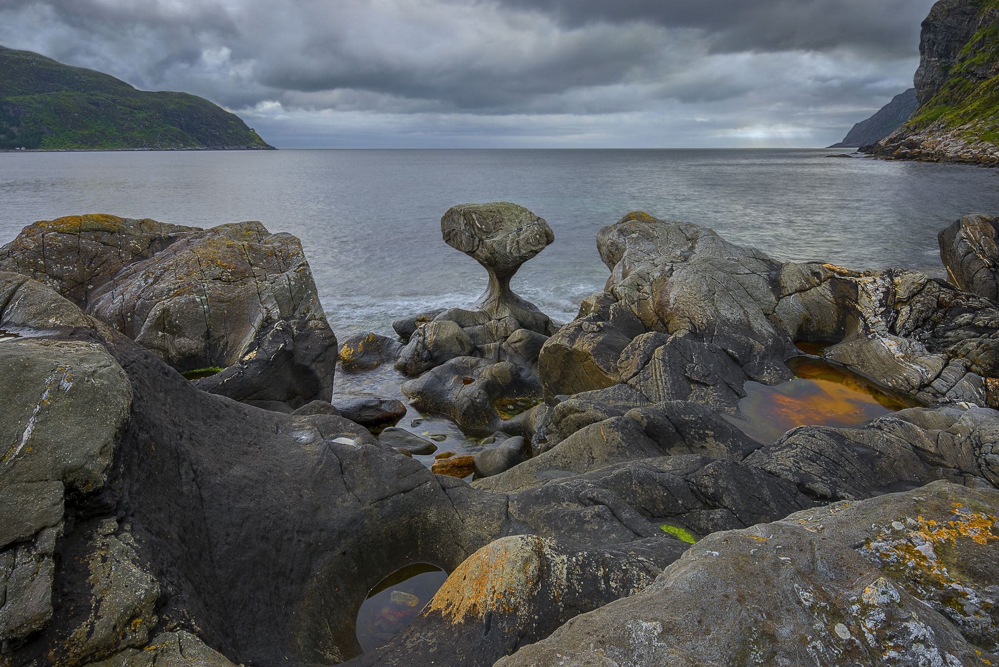 Norway, Unusual stone in Atlantic ocean coast. View on Kannesteinen and Kvalheimsvika. Over thousands of years, ocean waves have ground the rock to the special shape it has today. black and white