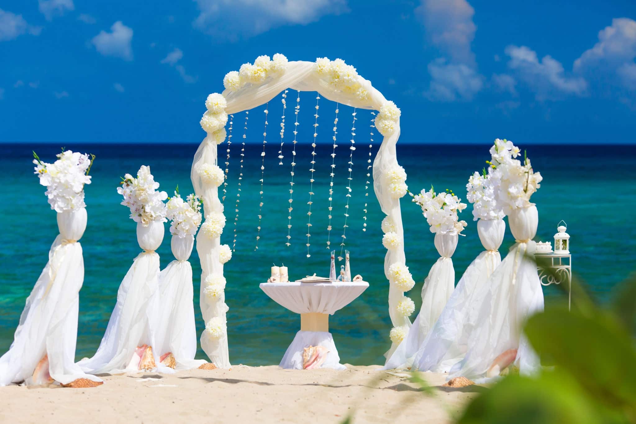 Accessory kit for a wedding is on the shores of the Caribbean Sea. Arch is decorated with curtains and flowers.