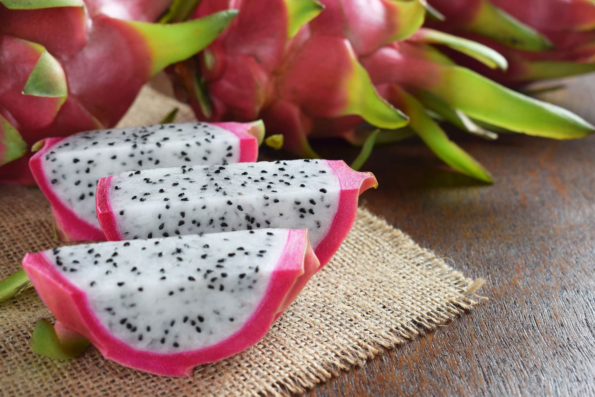 Healthy dragon fruits on sackcloth and brown wooden background