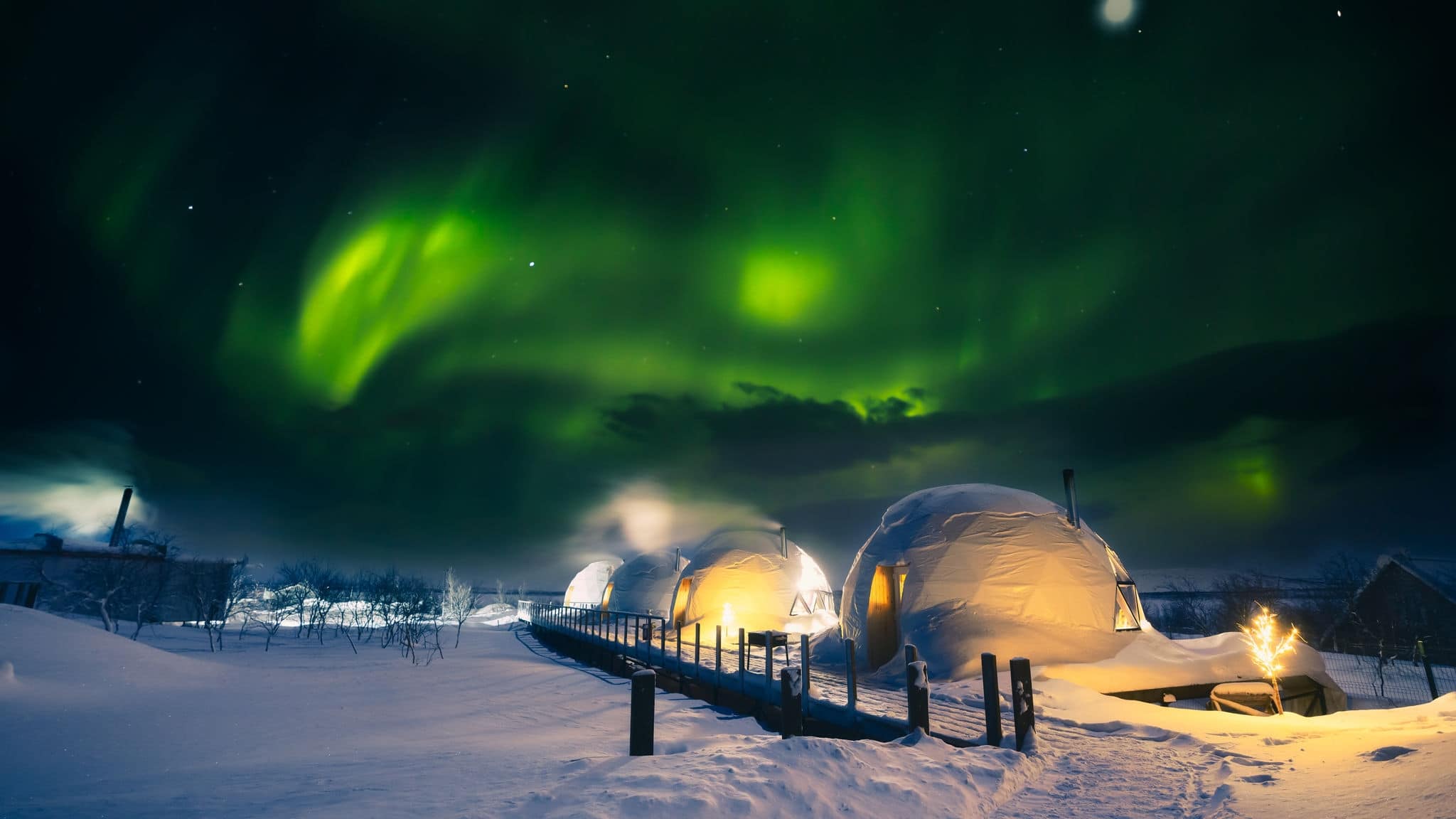 Northern Lights also known as aurora, borealis or polar lights at cold night over igloo village. Beautiful night photo of magic nature of winter landscape with grain.