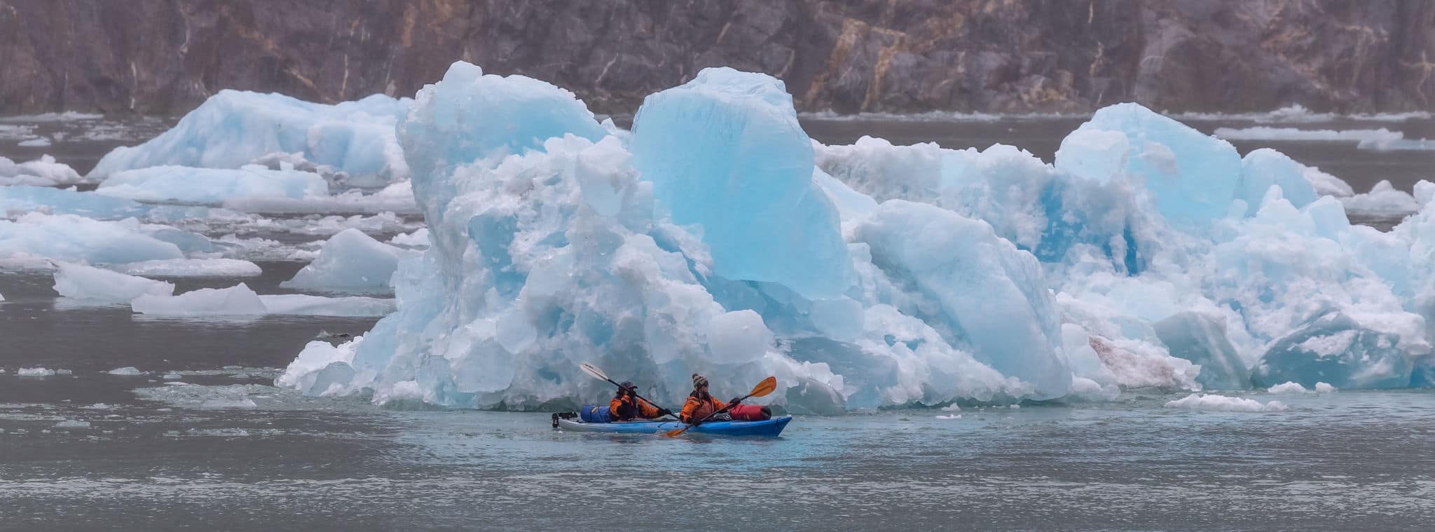 ALASKA, UNITED STATES - Aug 24, 2018: Tracy Arm Fjord, Alaska, US - August 23, 2018: Two tourists sailing in a kayak among huge icebergs in Alaska, USA