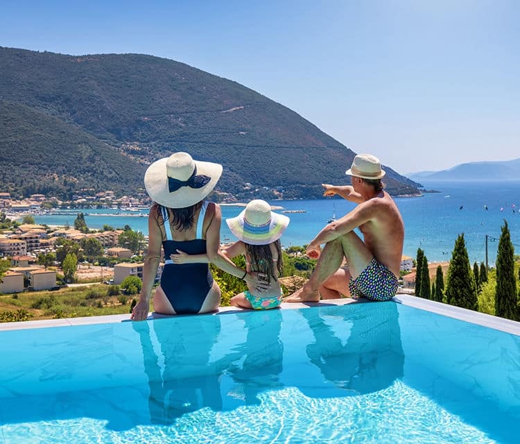 A family relaxes poolside overlooking the coastline.