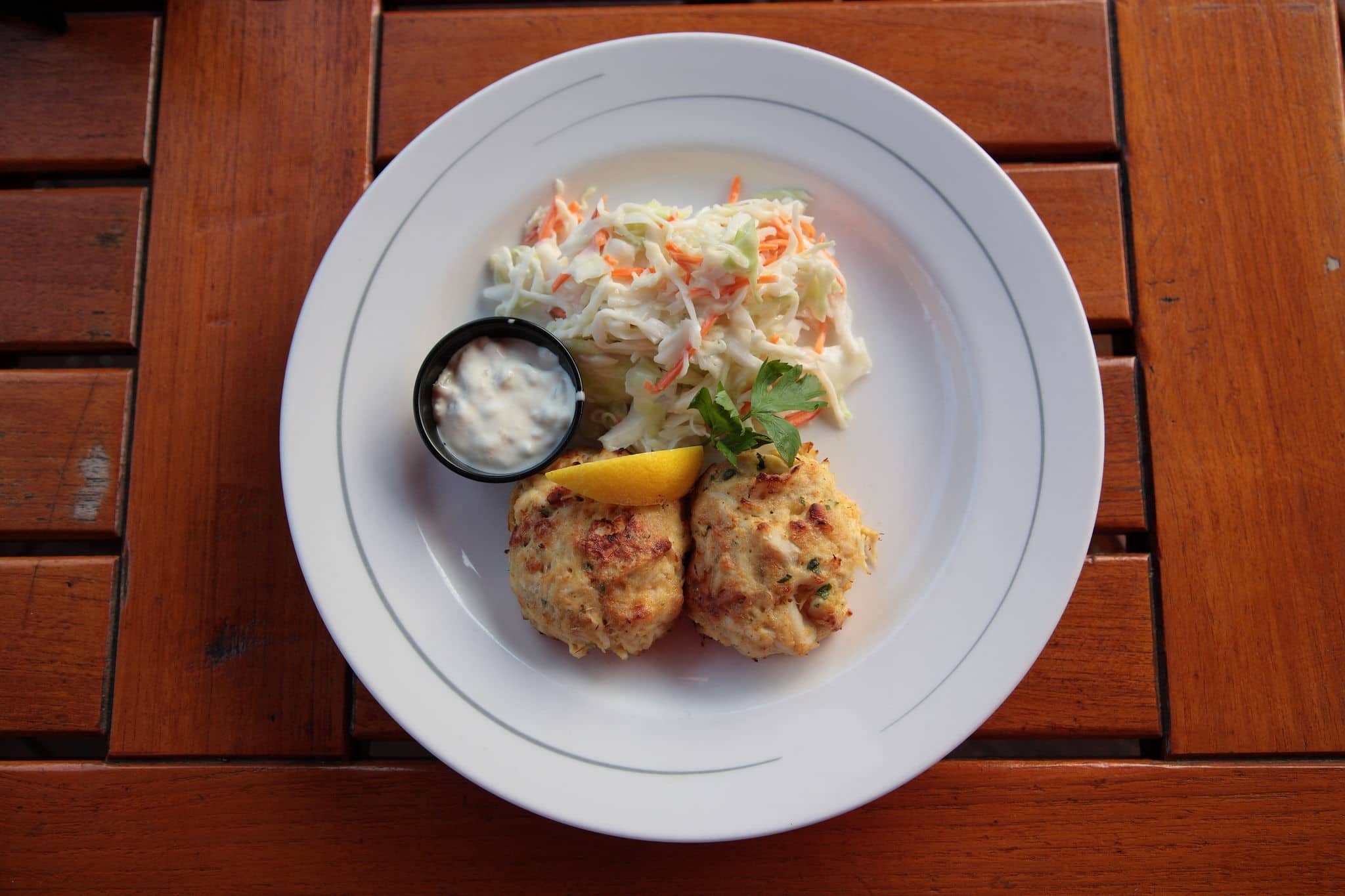 Close up of Typical Maryland Crab Cakes with salad and sauce on table from a famous restaurant at inner harbor in Baltimore, USA